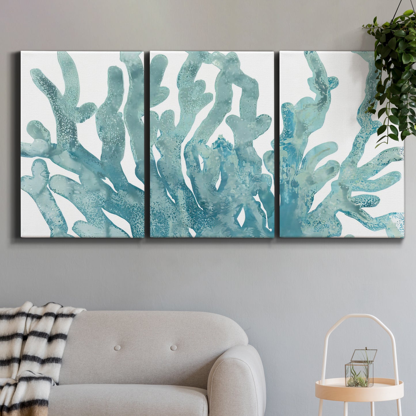 Three-panel canvas wall art featuring blue coral inspired watercolor, displayed in a modern living room above a sofa.