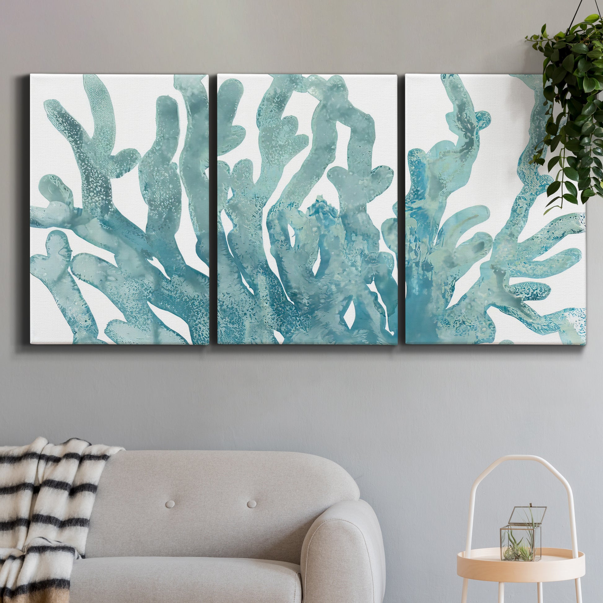 Three-panel canvas wall art featuring blue coral inspired watercolor, displayed in a modern living room above a sofa.