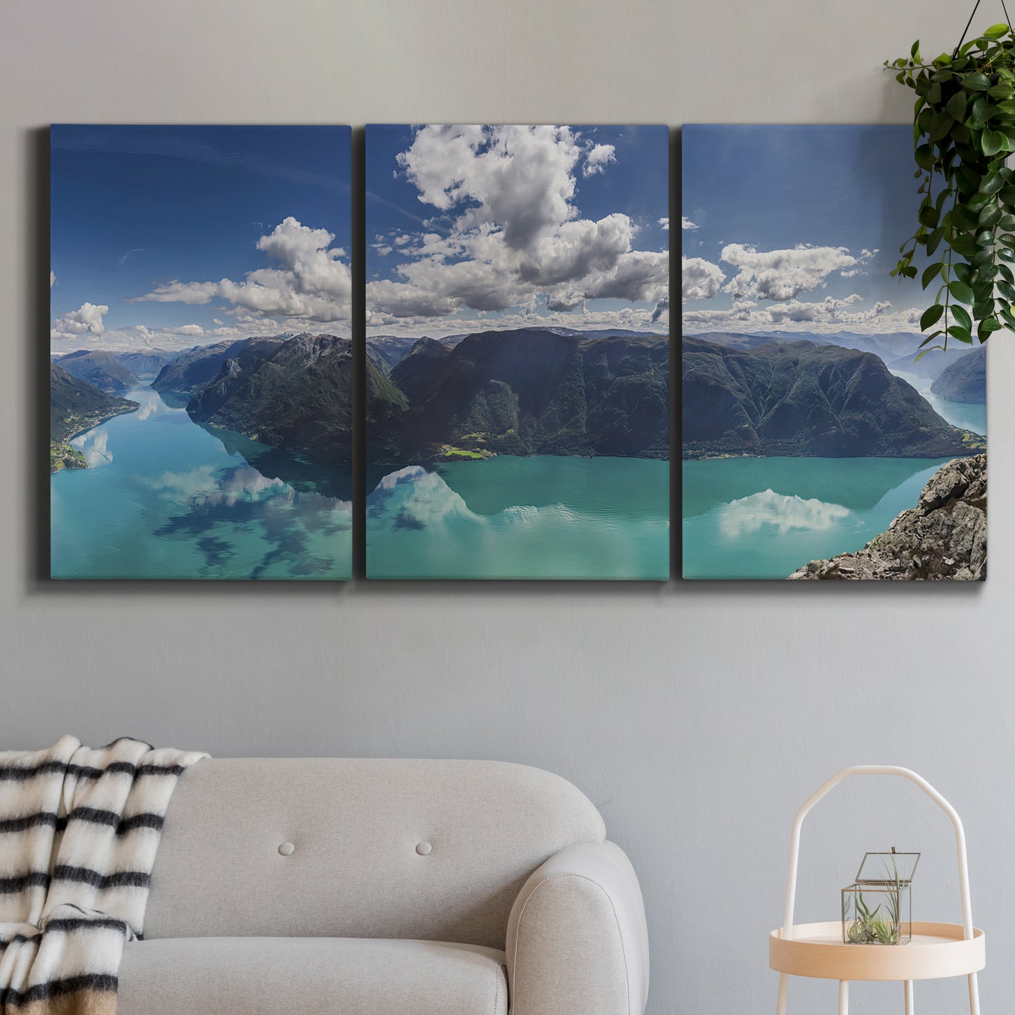 Three-panel canvas wall art featuring tropical water reflections with foliage, displayed in a modern living room above a sofa.