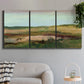 Three-panel canvas wall art featuring pastoral landscape with winding road, displayed in a modern living room above a sofa.