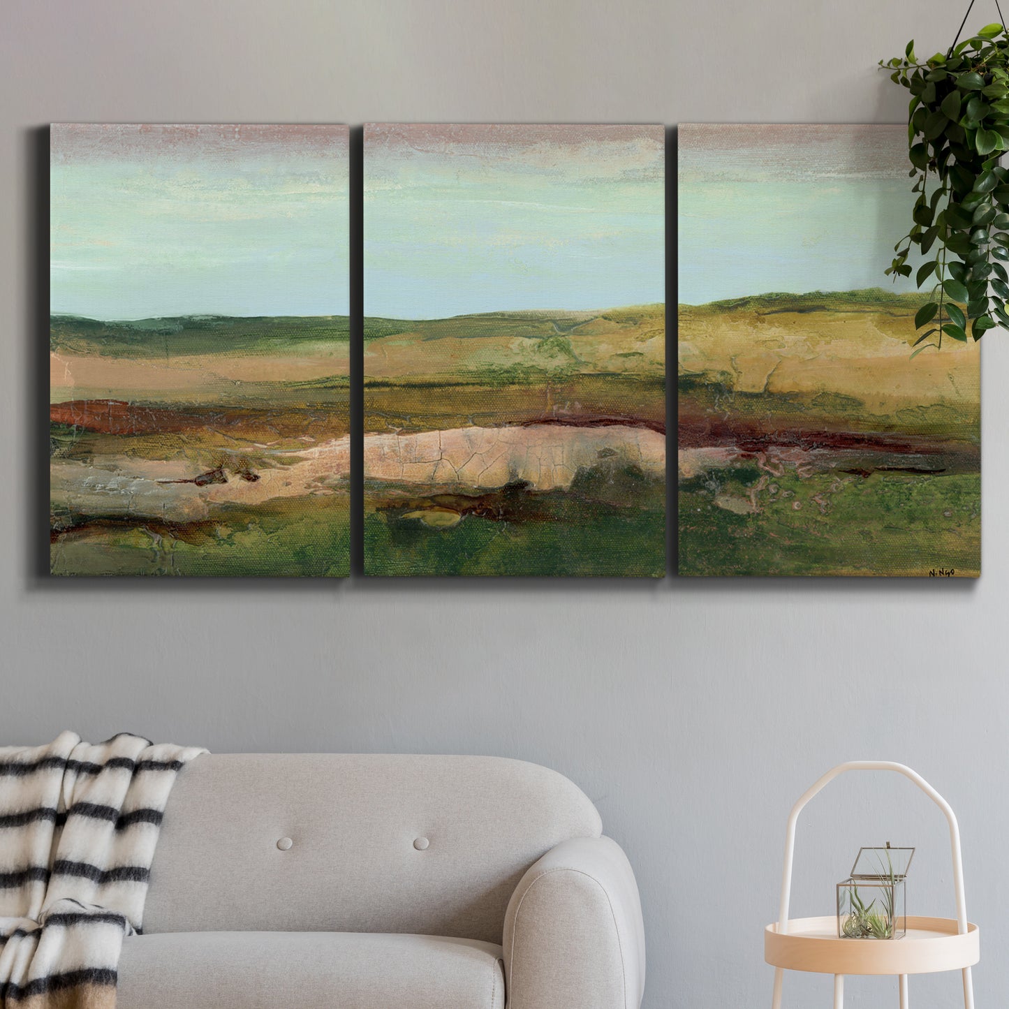 Three-panel canvas wall art featuring pastoral landscape with winding road, displayed in a modern living room above a sofa.