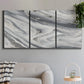 Three-panel canvas wall art featuring minimal monochrome abstract forms, displayed in a modern living room above a sofa.