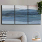Three-panel canvas wall art featuring wide lake with distant shoreline, displayed in a modern living room above a sofa.