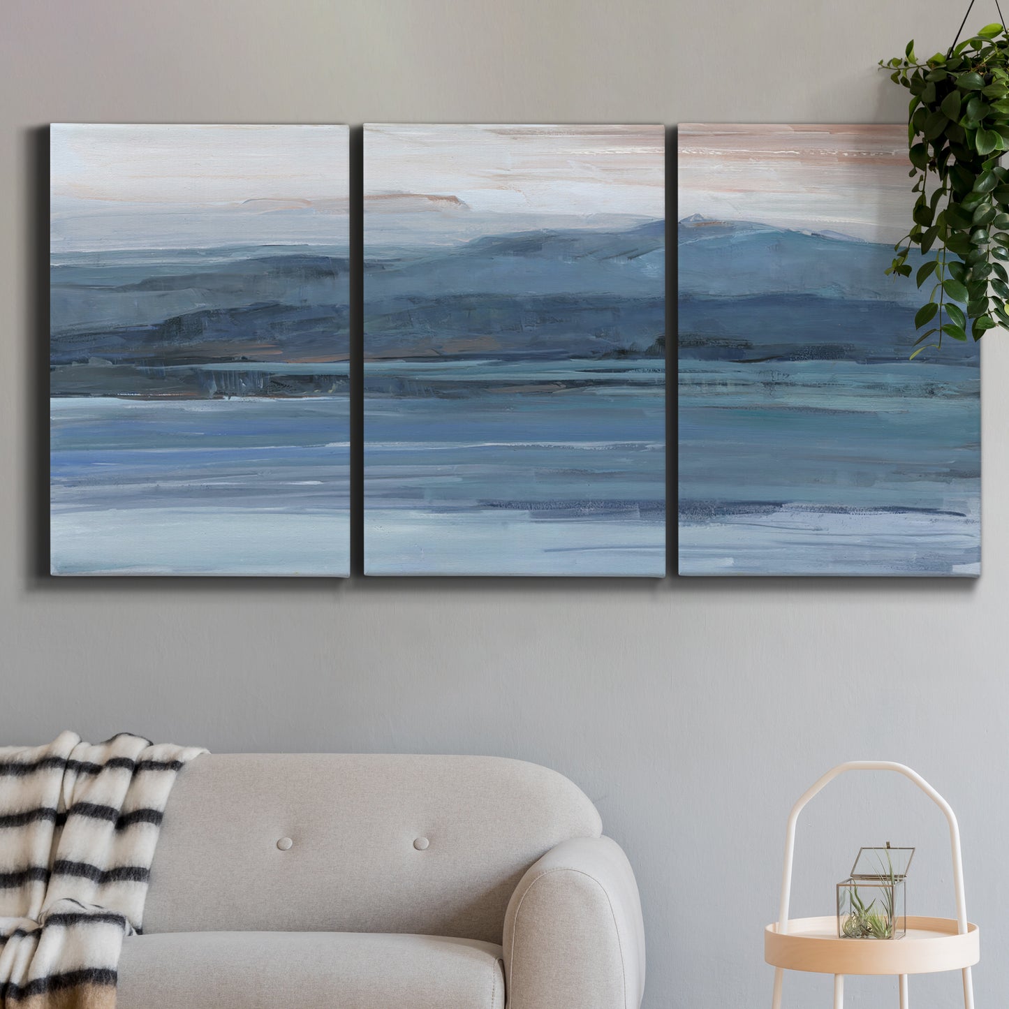 Three-panel canvas wall art featuring wide lake with distant shoreline, displayed in a modern living room above a sofa.
