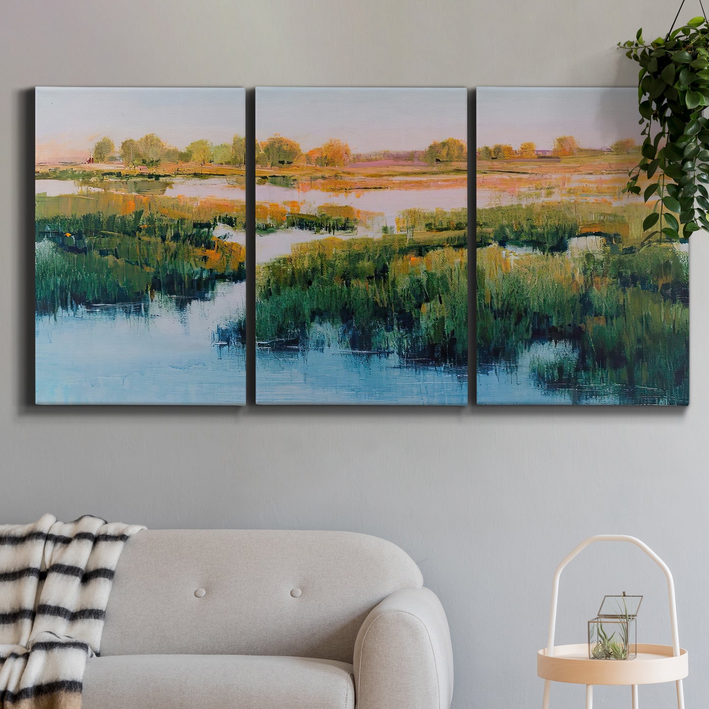 Three-panel canvas wall art featuring pastoral marshland landscape, displayed in a modern living room above a sofa.