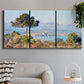 Three-panel canvas wall art featuring coastal town viewed from hillside, displayed in a modern living room above a sofa.
