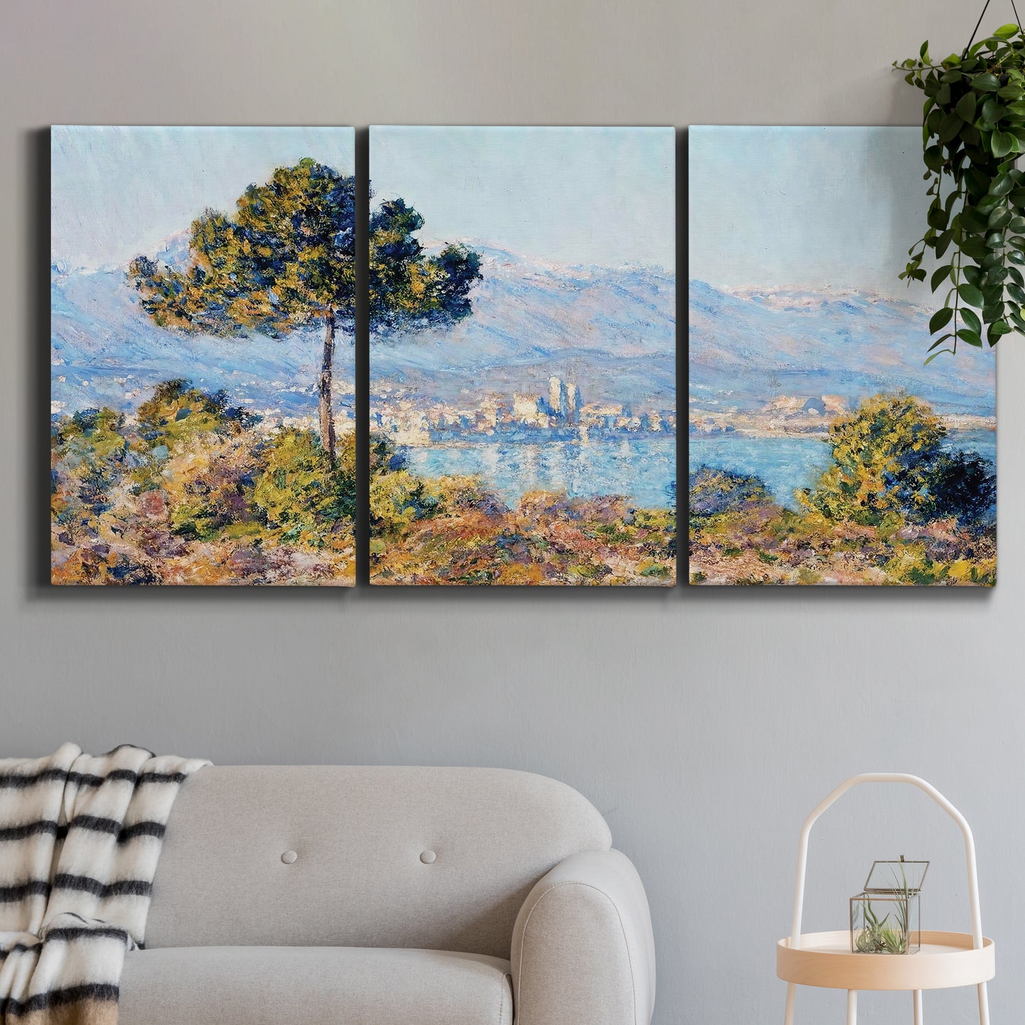 Three-panel canvas wall art featuring coastal town viewed from hillside, displayed in a modern living room above a sofa.