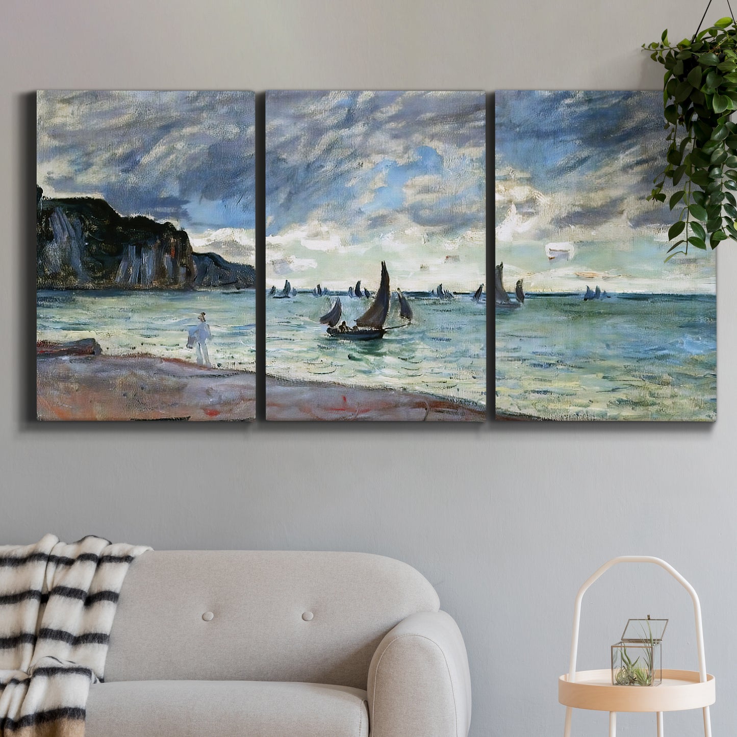 Three-panel canvas wall art featuring figures walking along sandy shoreline, displayed in a modern living room above a sofa.