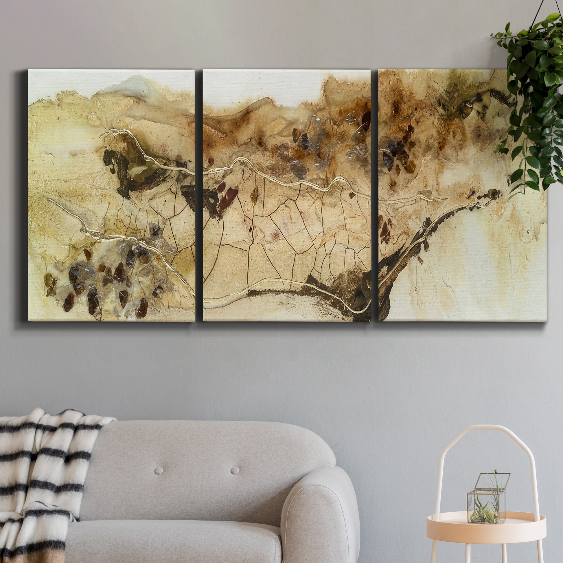 Three-panel canvas wall art featuring muted abstract with metallic gold accents, displayed in a modern living room above a sofa.