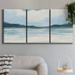 Three-panel canvas wall art featuring soft coastal shoreline landscape, displayed in a modern living room above a sofa.