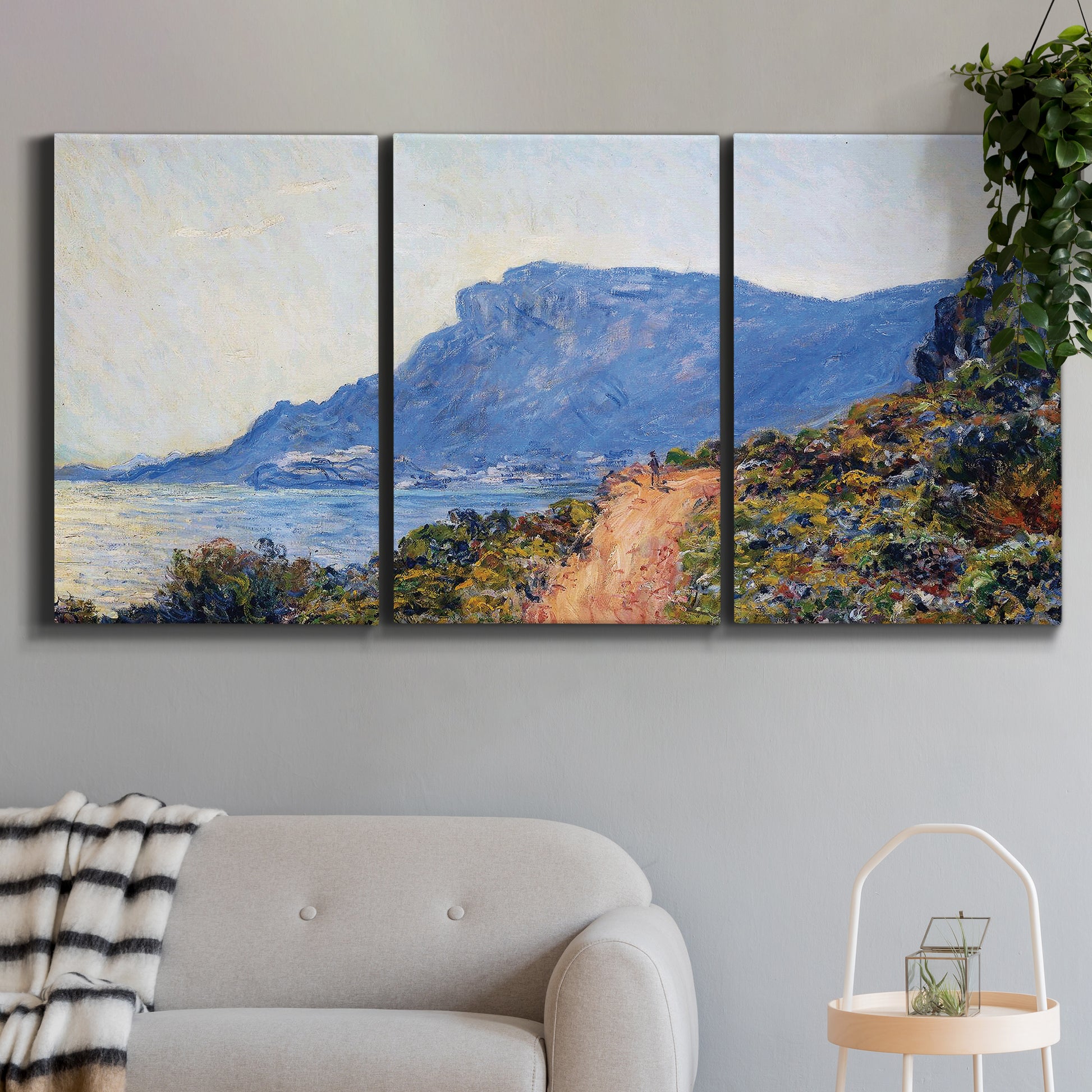 Three-panel canvas wall art featuring winding coastal road above sea, displayed in a modern living room above a sofa.