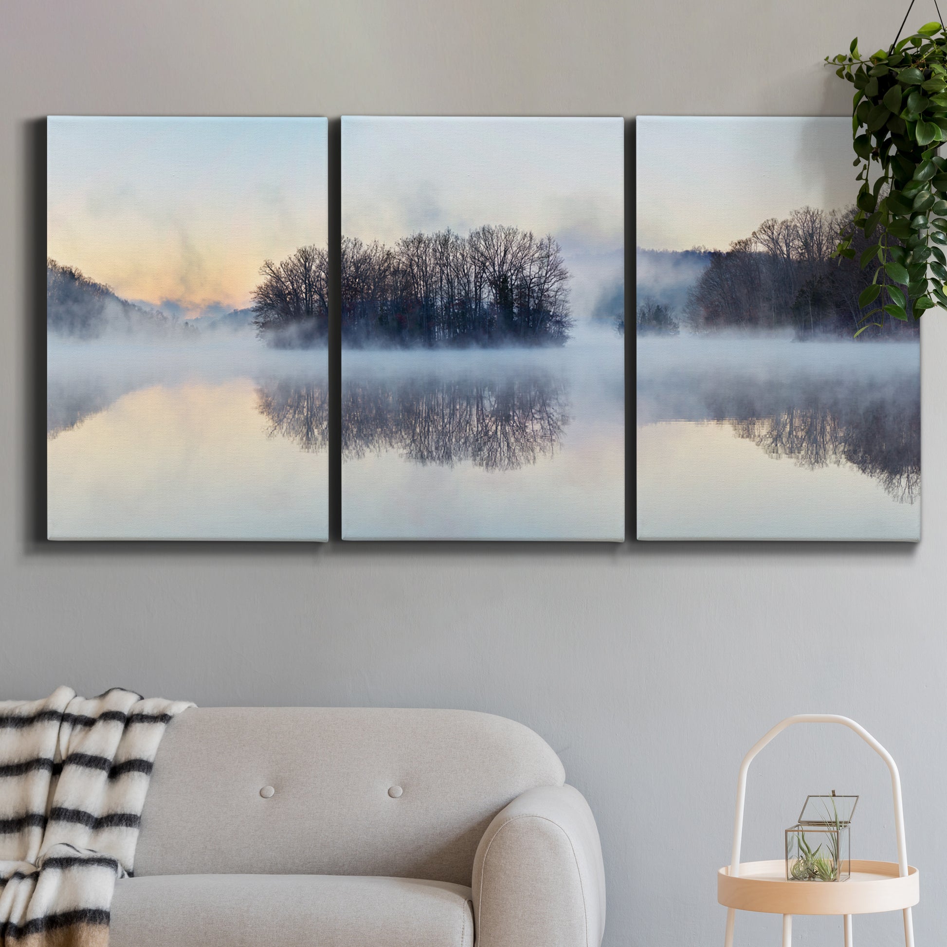 Three-panel canvas wall art featuring misty water landscape photograph, displayed in a modern living room above a sofa.