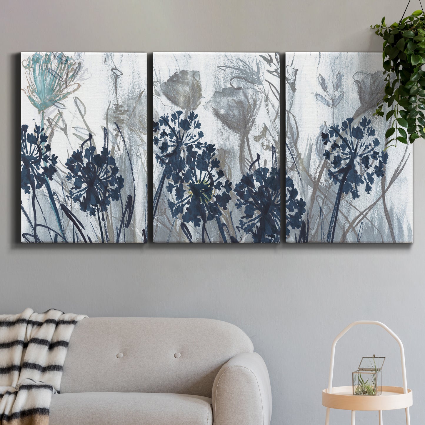 Three-panel canvas wall art featuring indigo floral abstraction, displayed in a modern living room above a sofa.