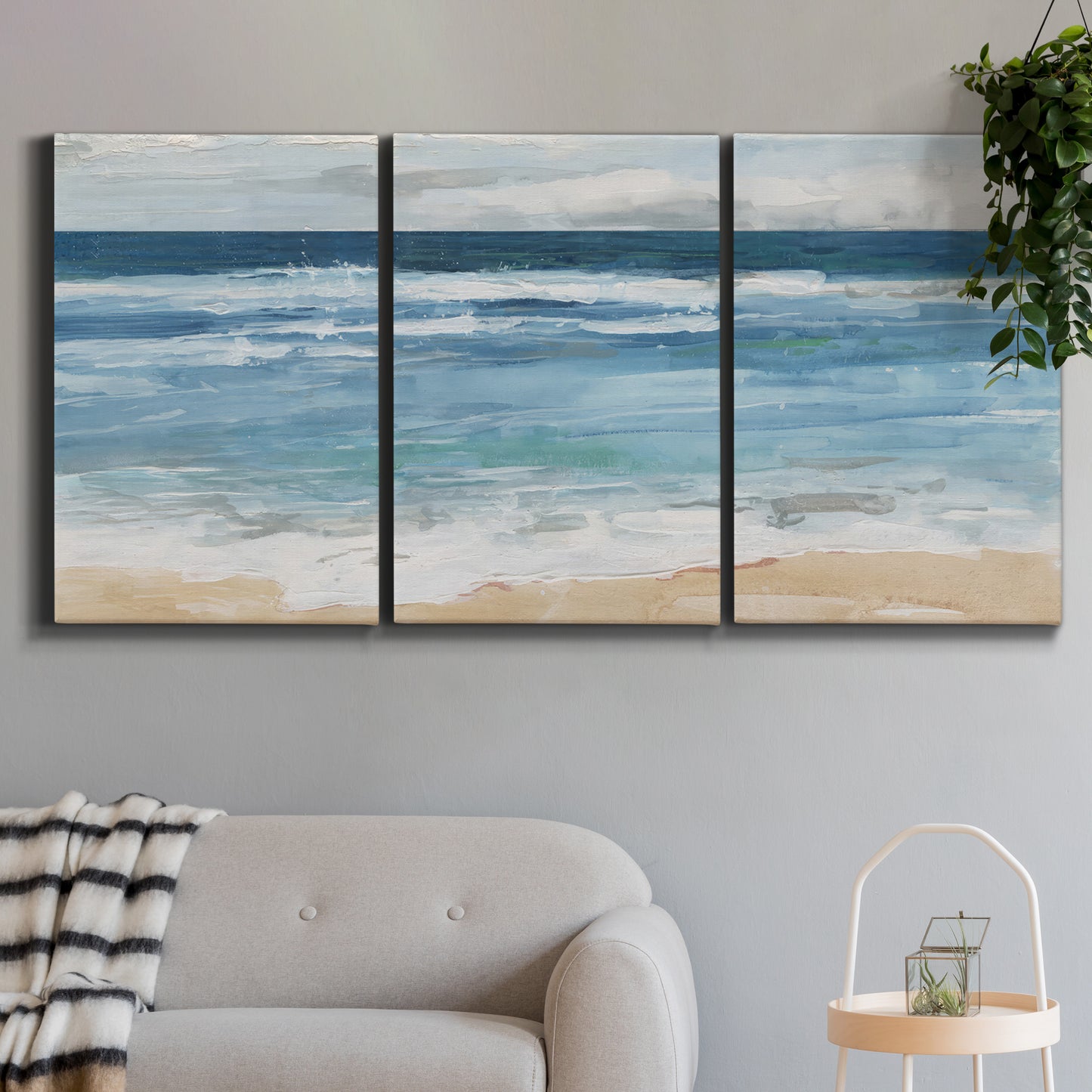 Three-panel canvas wall art featuring rolling ocean waves near shore, displayed in a modern living room above a sofa.