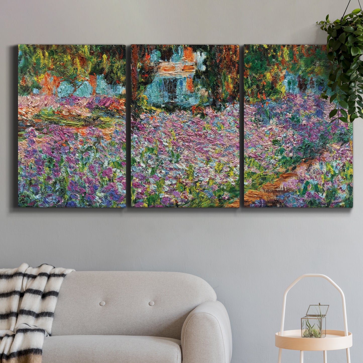 Three-panel canvas wall art featuring blooming irises in garden bed, displayed in a modern living room above a sofa.