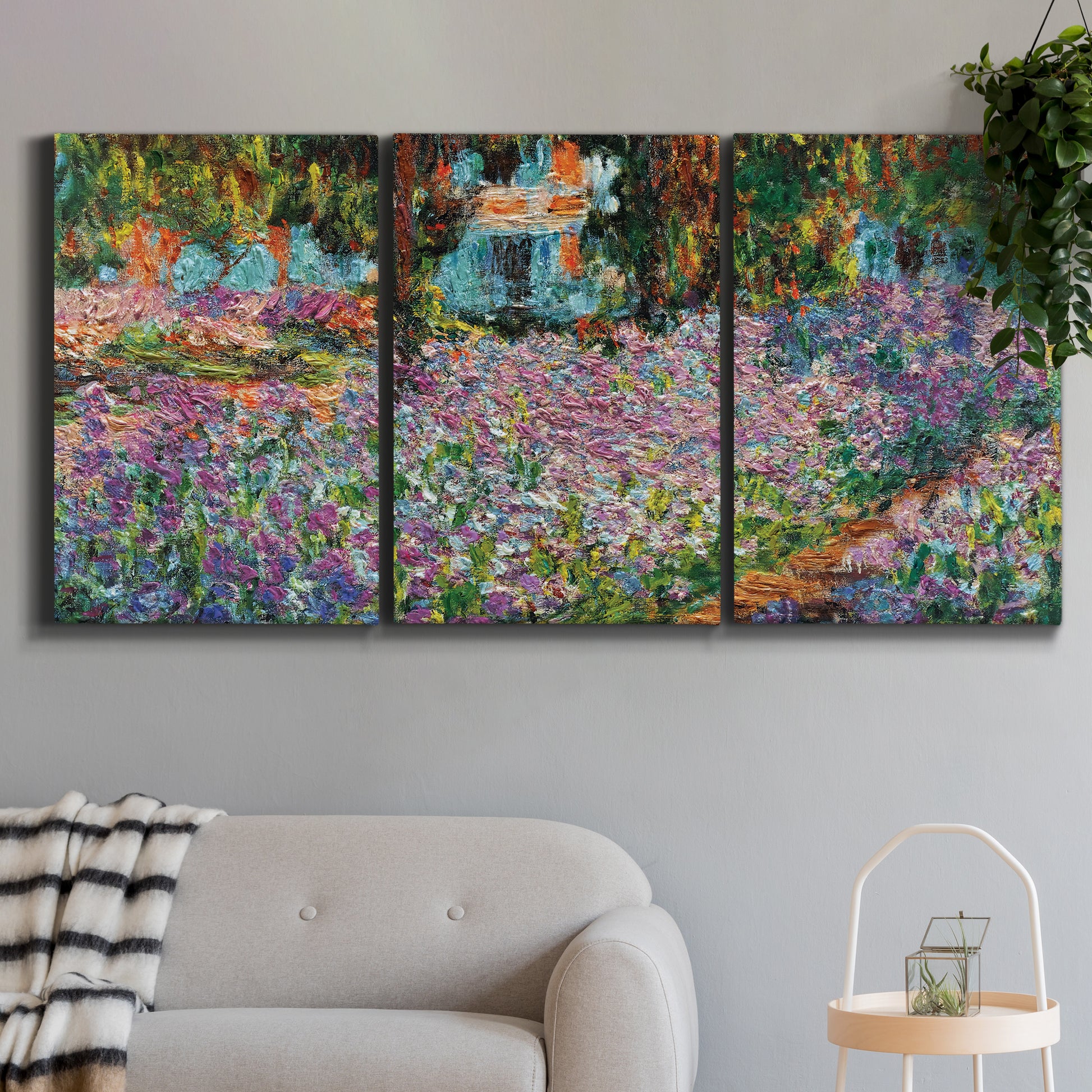 Three-panel canvas wall art featuring blooming irises in garden bed, displayed in a modern living room above a sofa.