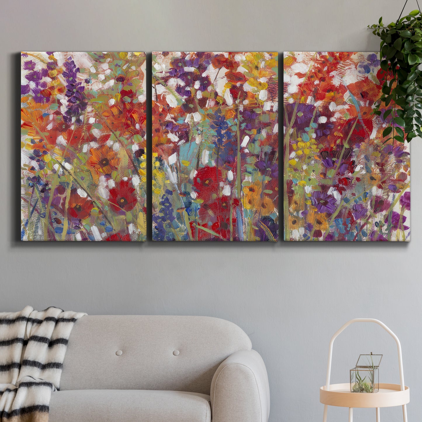 Three-panel canvas wall art featuring colorful floral arrangement, displayed in a modern living room above a sofa.
