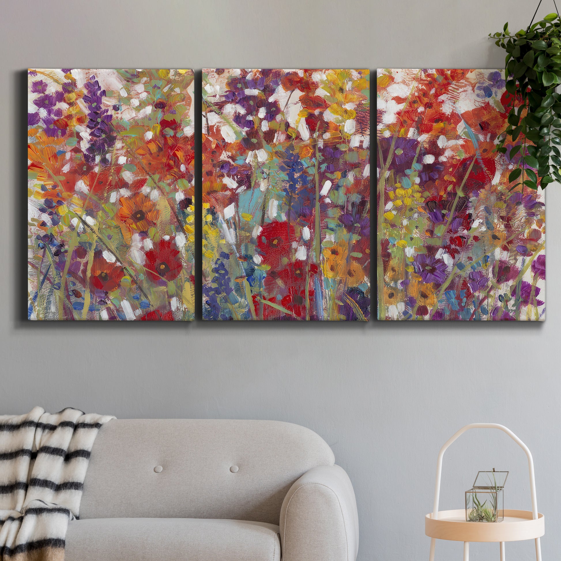 Three-panel canvas wall art featuring colorful floral arrangement, displayed in a modern living room above a sofa.
