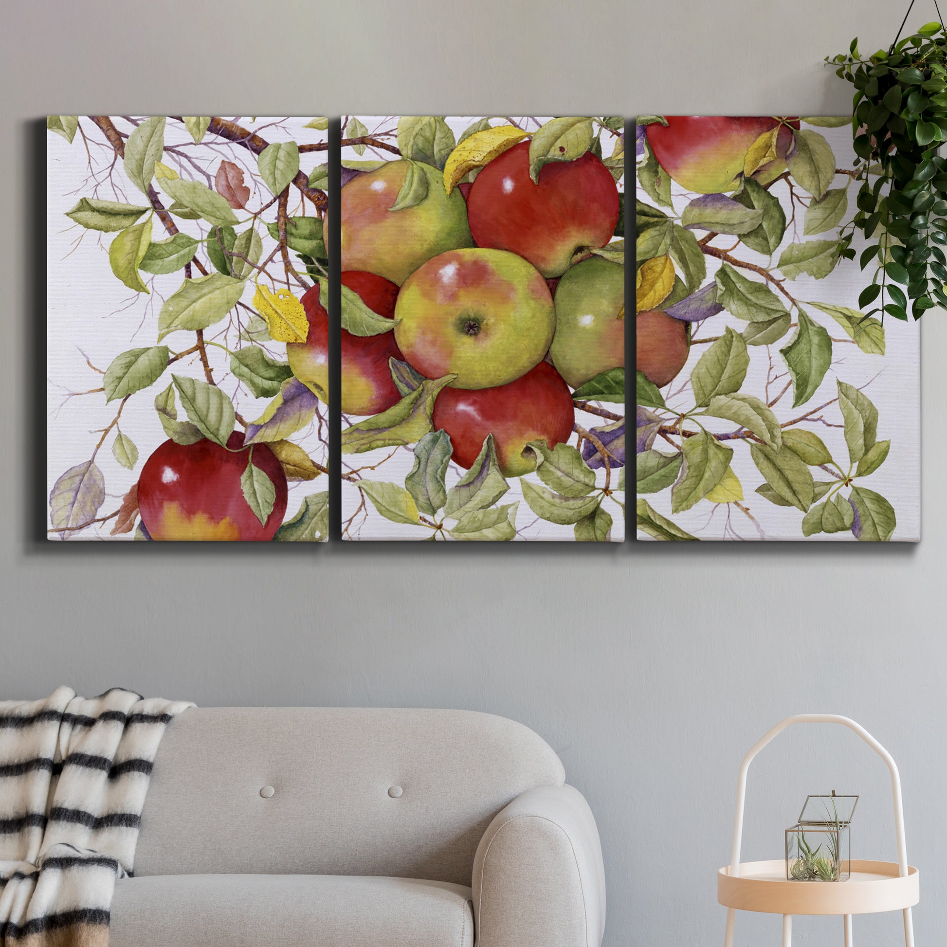 Three-panel canvas wall art featuring apples hanging from branch, displayed in a modern living room above a sofa.