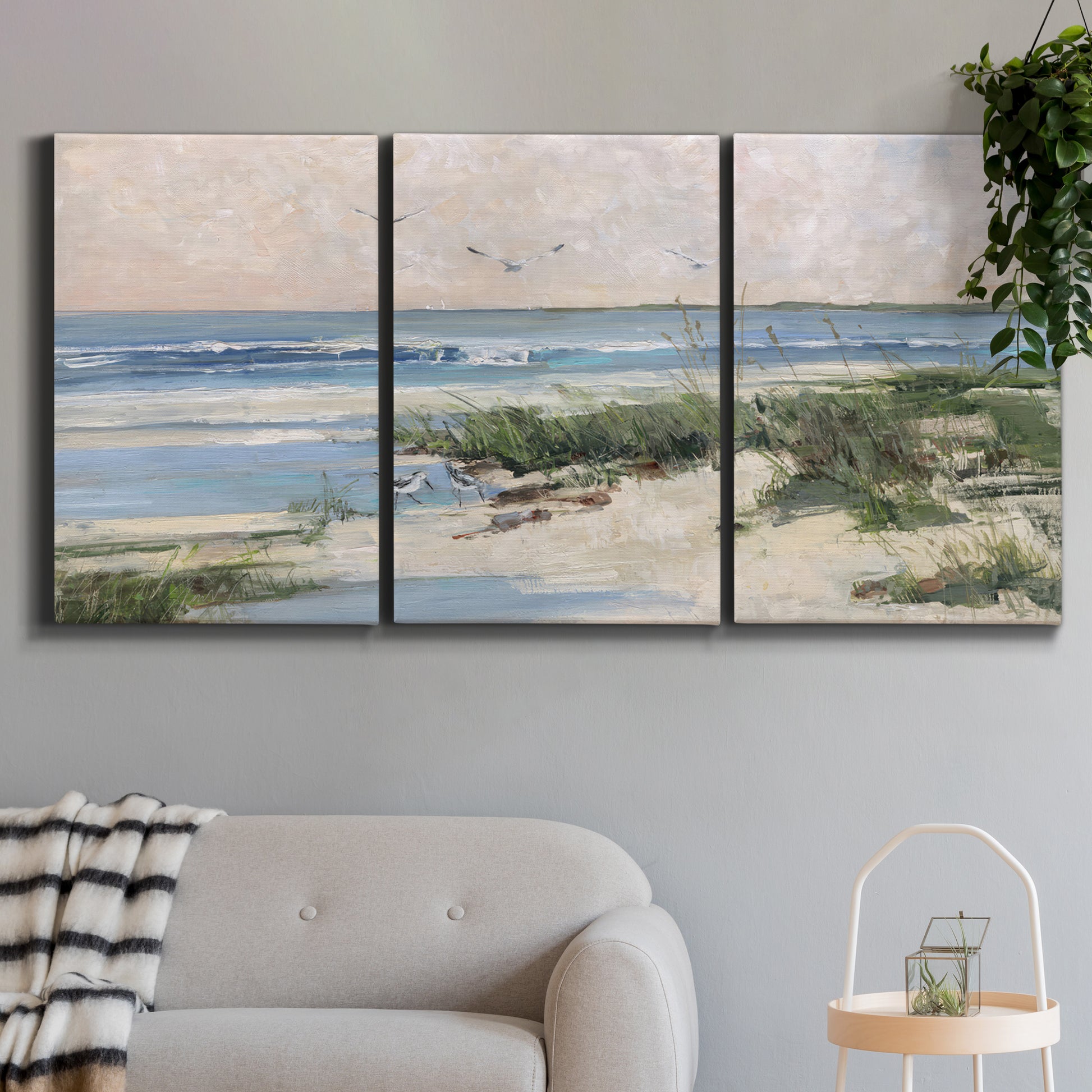 Three-panel canvas wall art featuring soft morning light over calm sea, displayed in a modern living room above a sofa.
