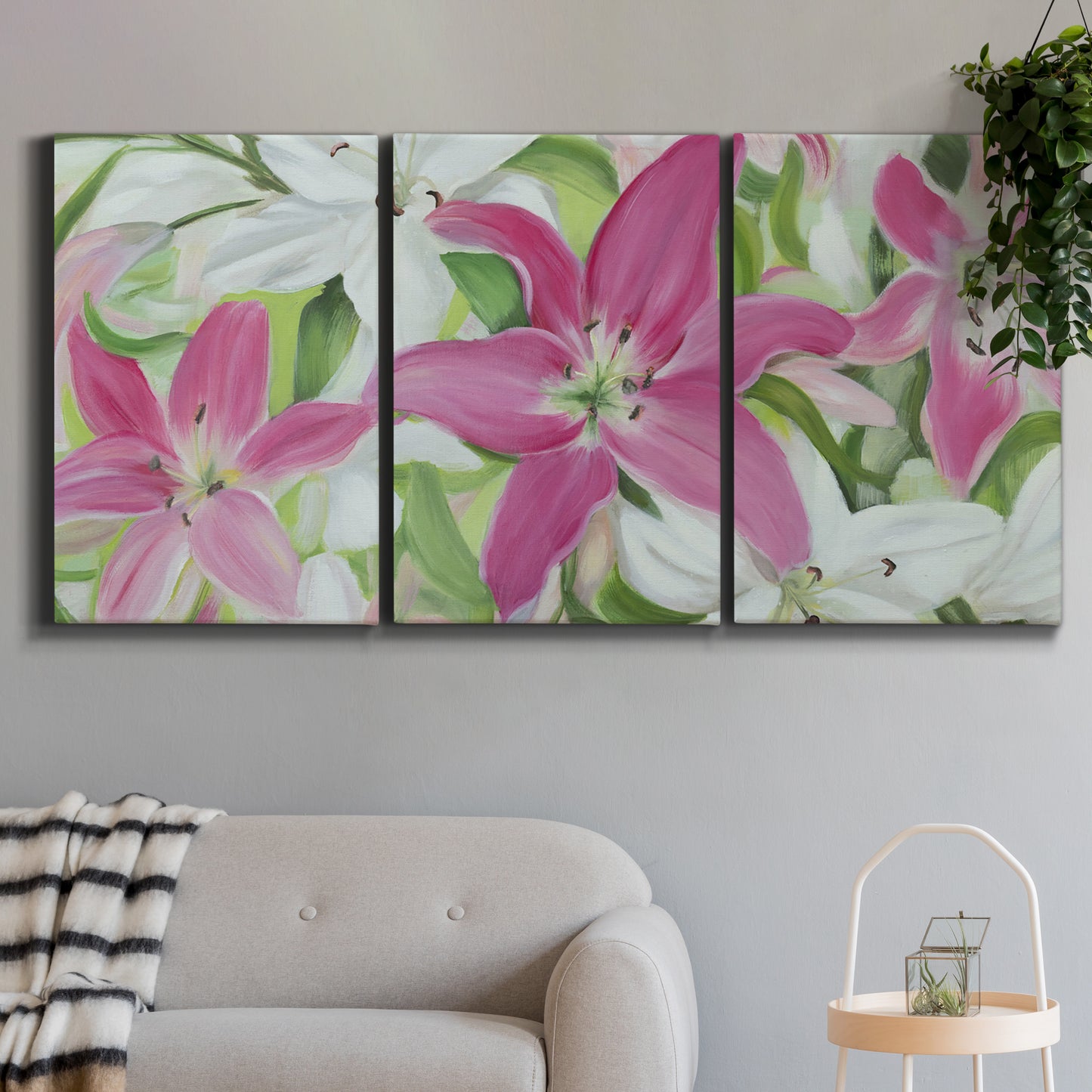 Three-panel canvas wall art featuring pink and white lilies in bloom, displayed in a modern living room above a sofa.