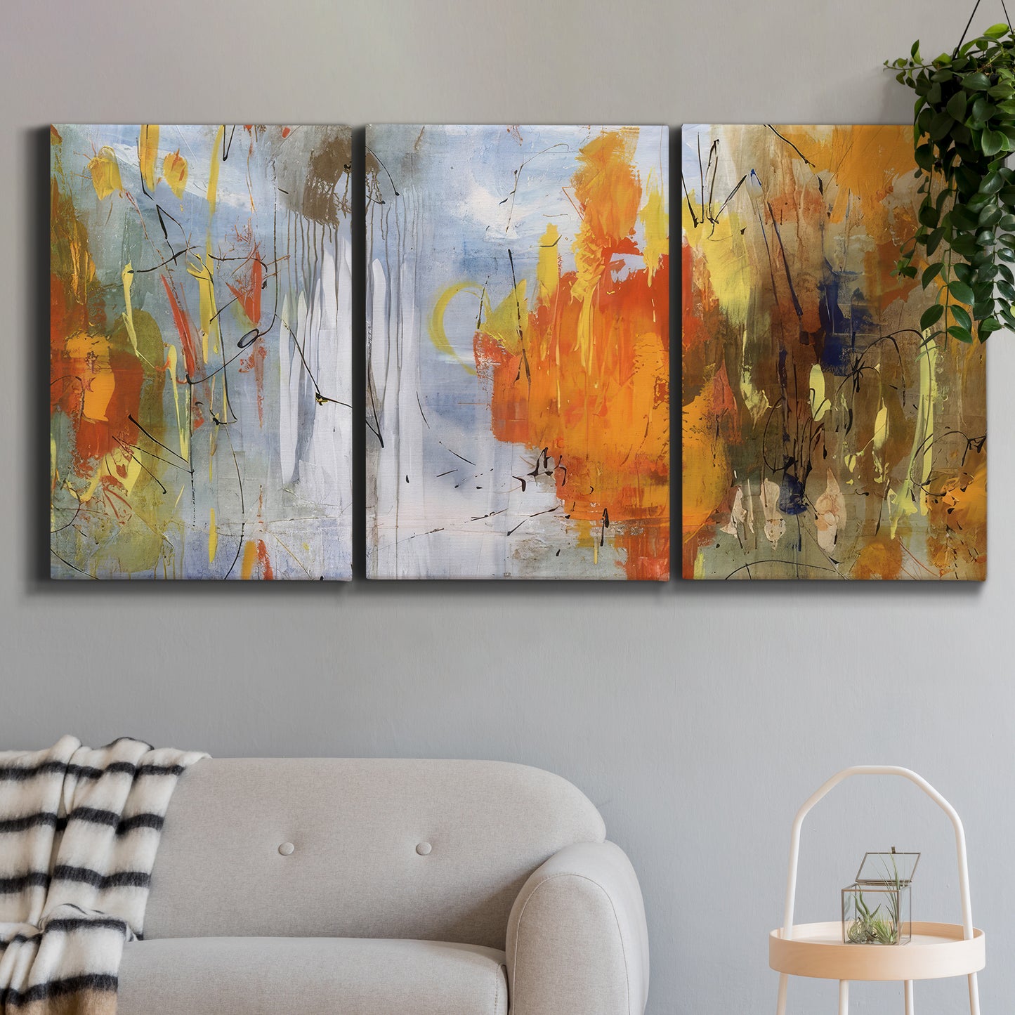 Three-panel canvas wall art featuring abstract warm sunset tones, displayed in a modern living room above a sofa.