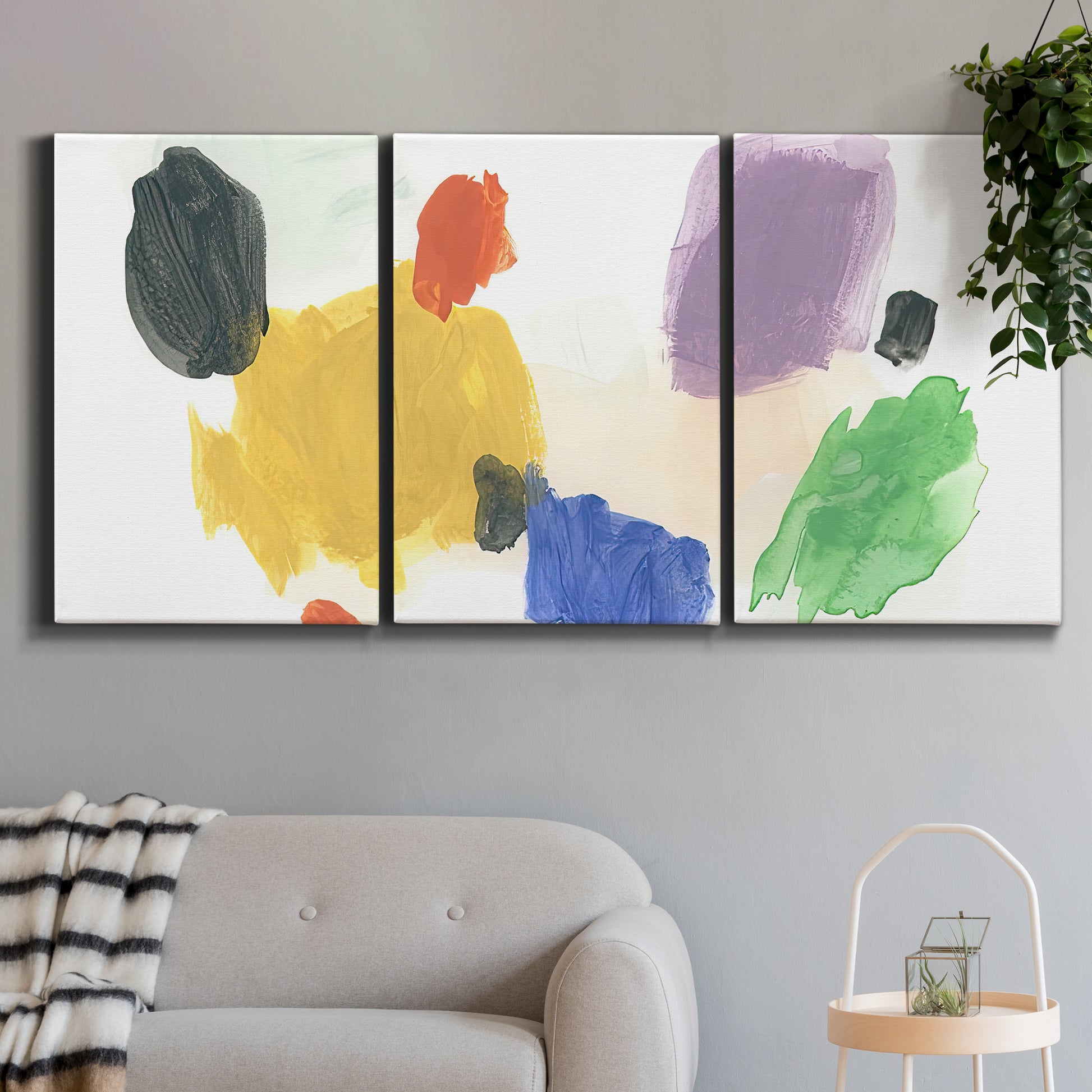 Three-panel canvas wall art featuring inkblot style abstract color symmetry, displayed in a modern living room above a sofa.