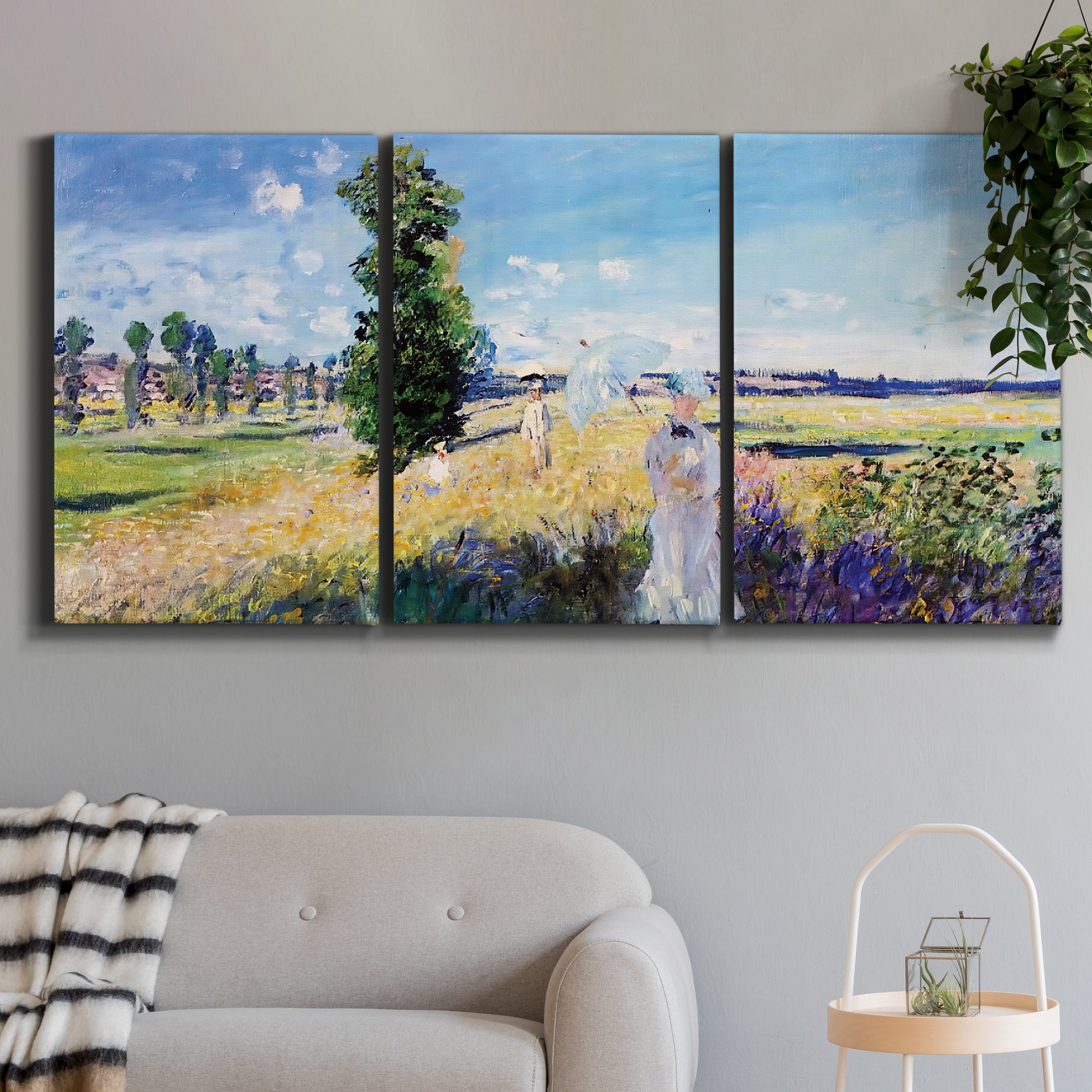 Three-panel canvas wall art featuring riverside path with figures, displayed in a modern living room above a sofa.