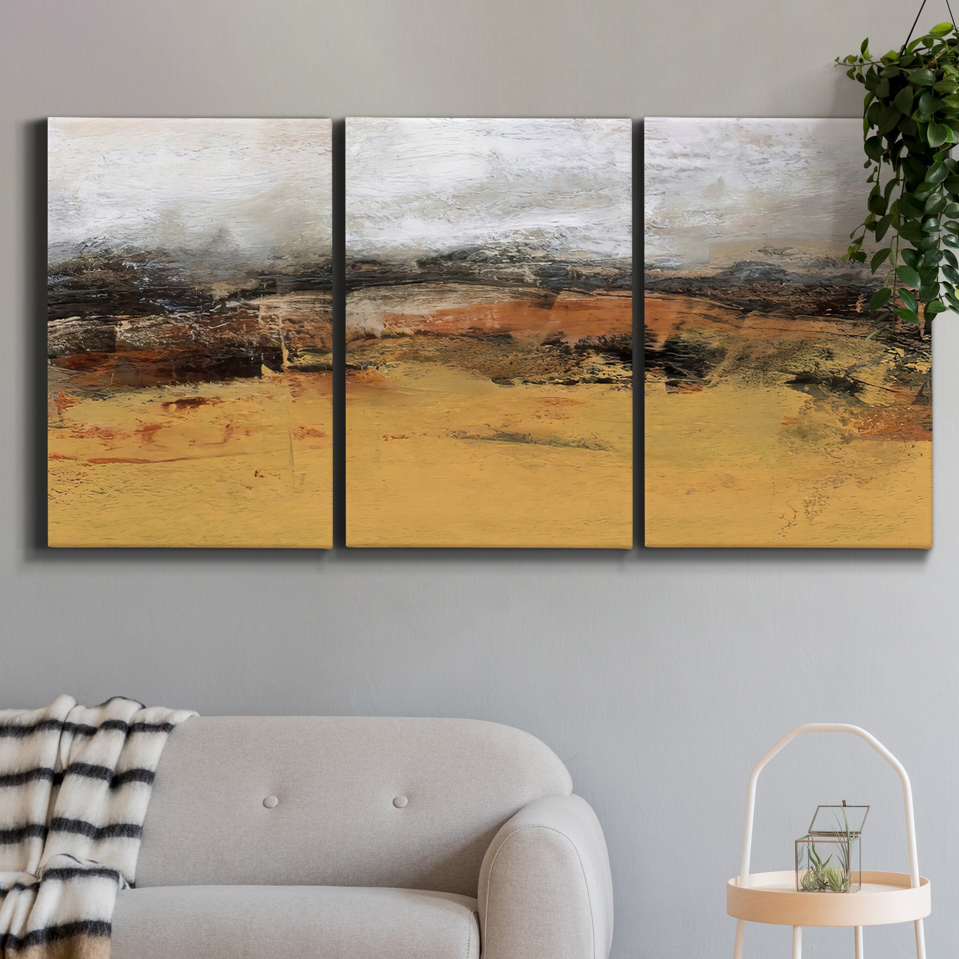 Three-panel canvas wall art featuring abstract bridge landscape in ochre, displayed in a modern living room above a sofa.