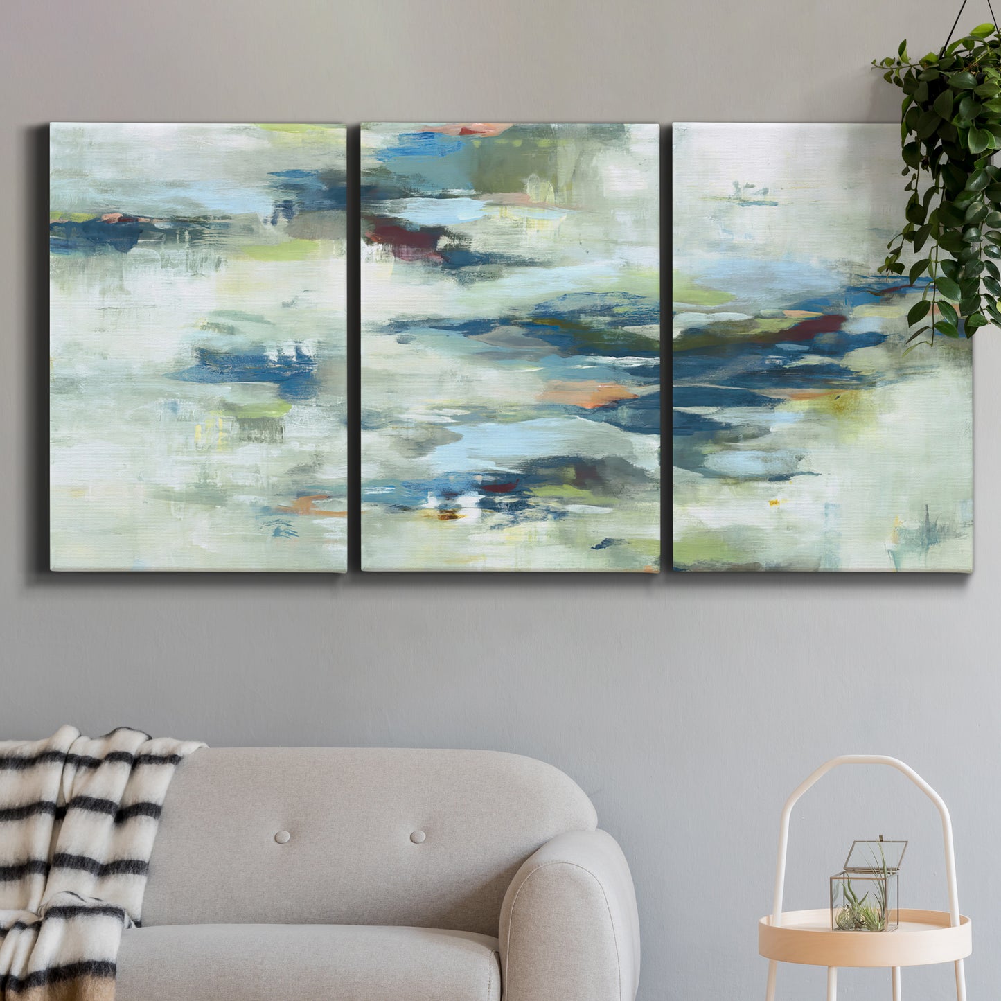 Three-panel canvas wall art featuring dreamlike abstract drifting motion, displayed in a modern living room above a sofa.
