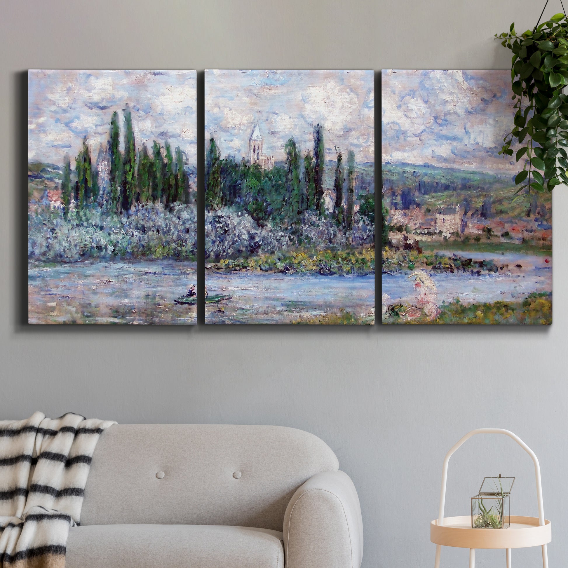 Three-panel canvas wall art featuring summer village view along river, displayed in a modern living room above a sofa.