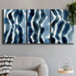 Three-panel canvas wall art featuring flowing blue watercolor wave forms, displayed in a modern living room above a sofa.