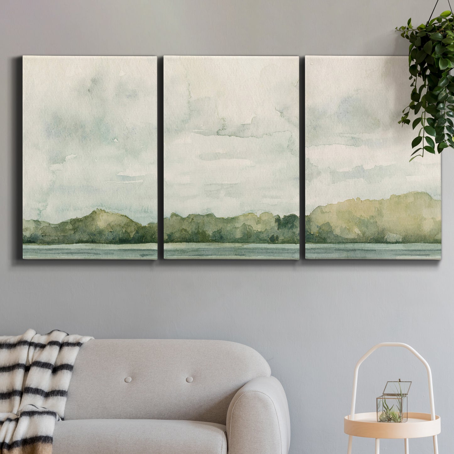 Three-panel canvas wall art featuring riverbank landscape with trees, displayed in a modern living room above a sofa.