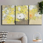 Three-panel canvas wall art featuring abstract floral table arrangement, displayed in a modern living room above a sofa.