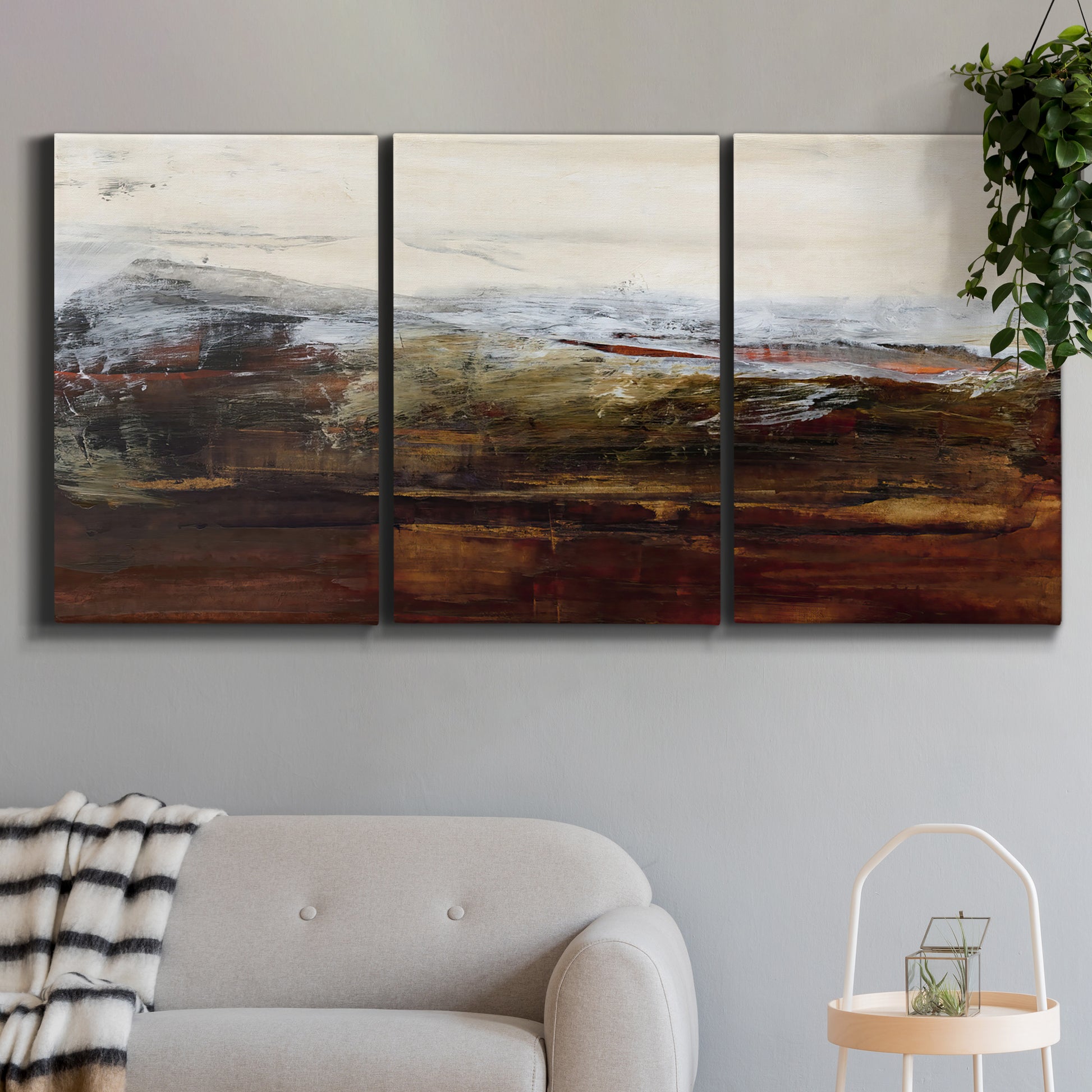 Three-panel canvas wall art featuring rustic abstract landscape exploration, displayed in a modern living room above a sofa.