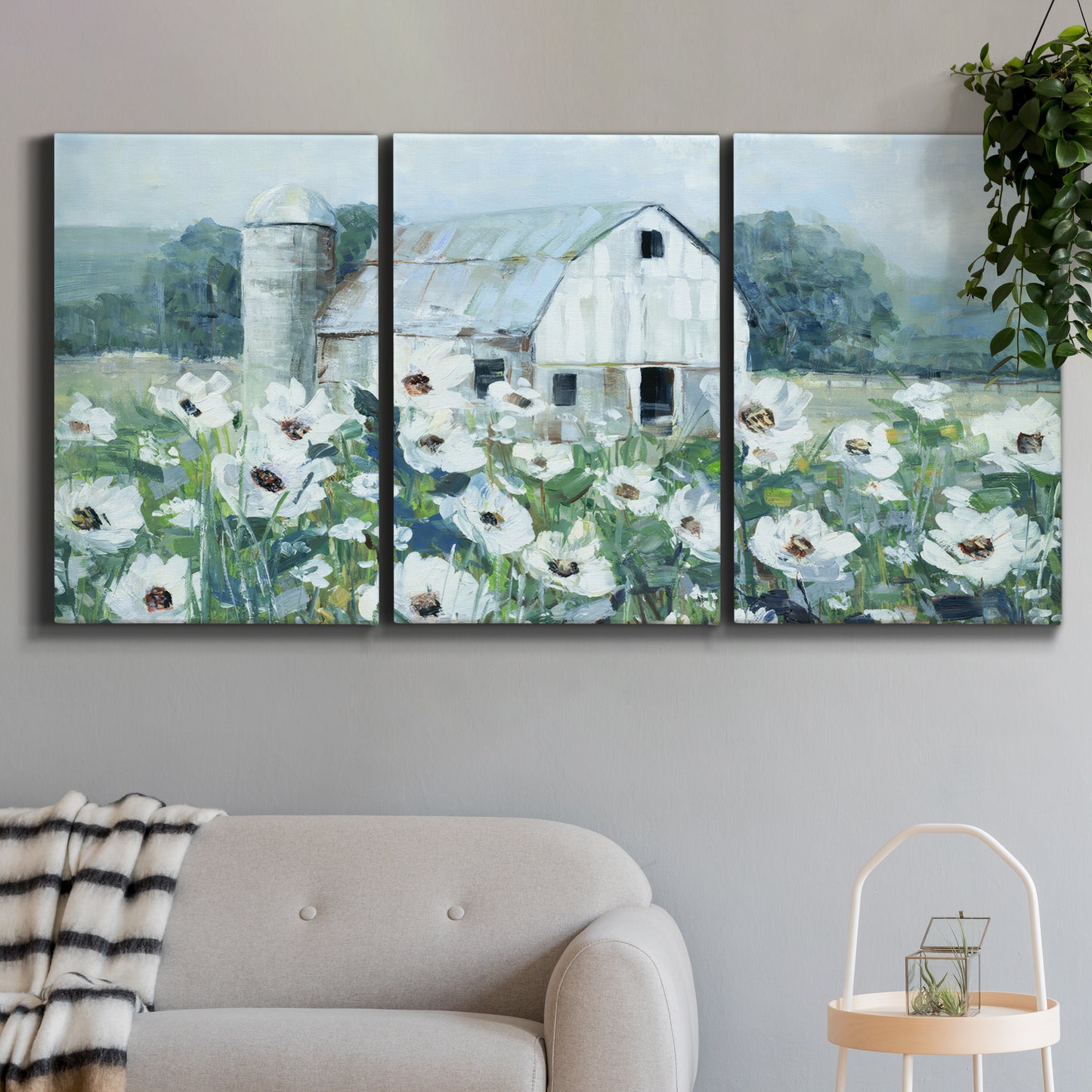 Three-panel canvas wall art featuring pastoral farmland with open fields, displayed in a modern living room above a sofa.