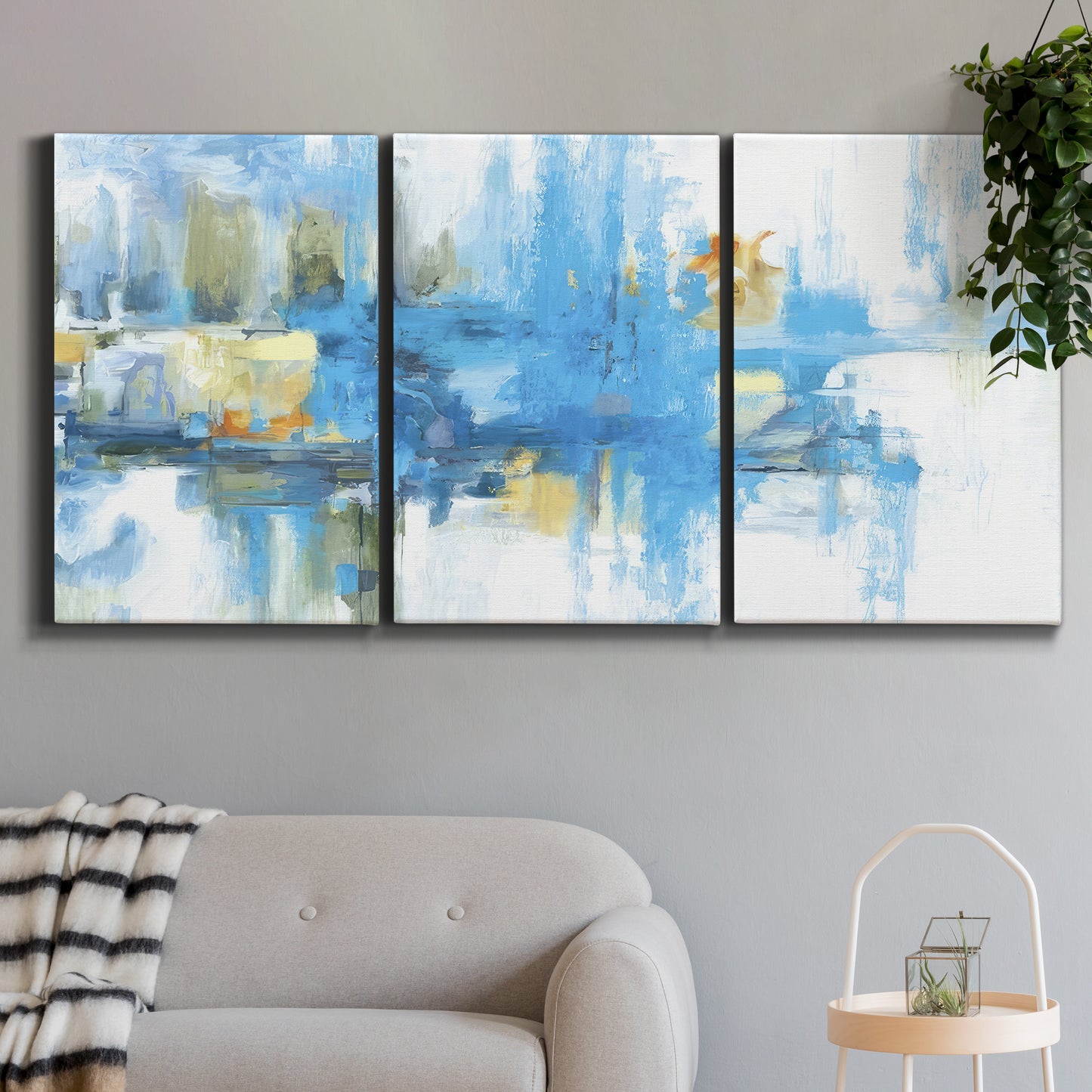 Three-panel canvas wall art featuring blue toned abstract city rhythm, displayed in a modern living room above a sofa.