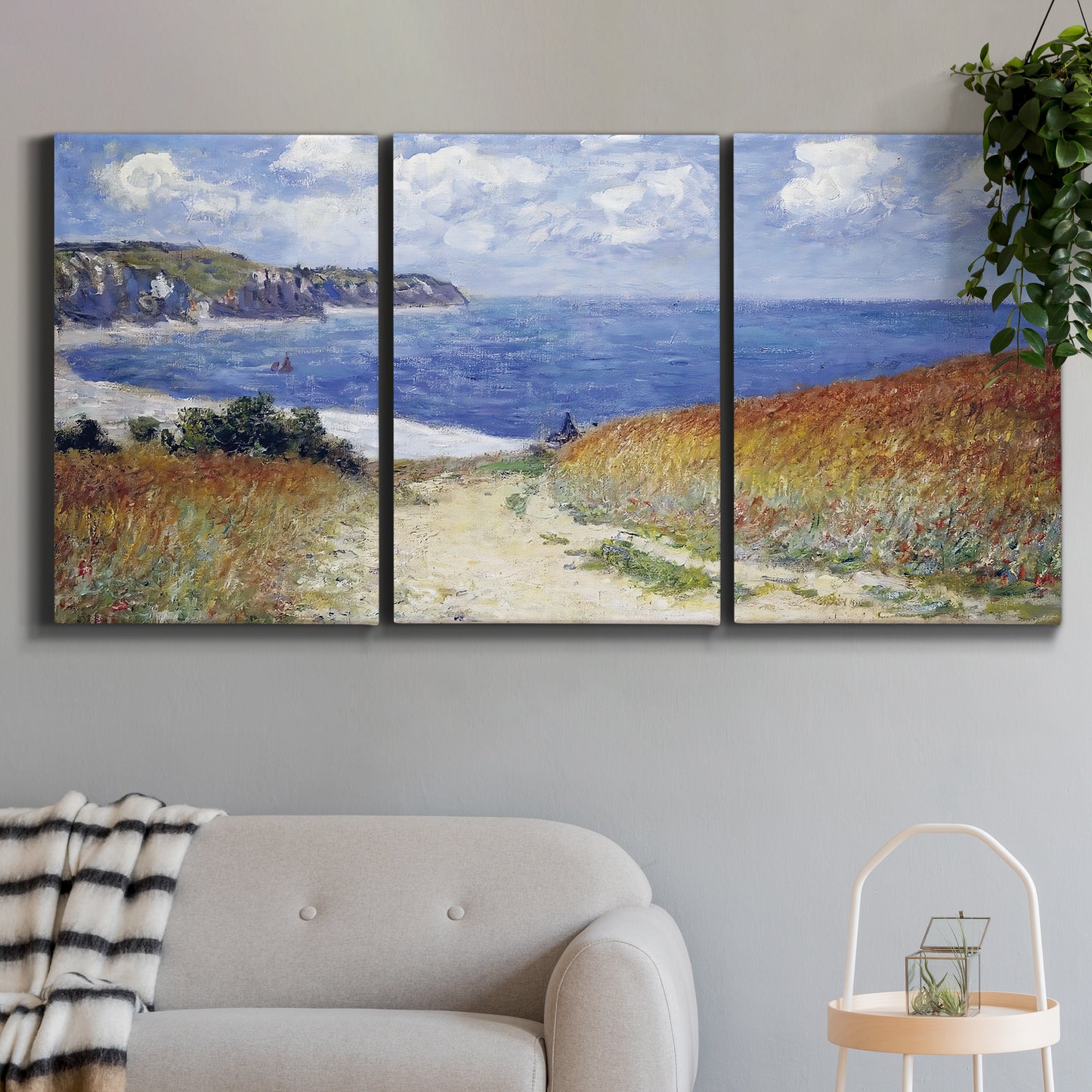 Three-panel canvas wall art featuring coastal path leading to sea, displayed in a modern living room above a sofa.