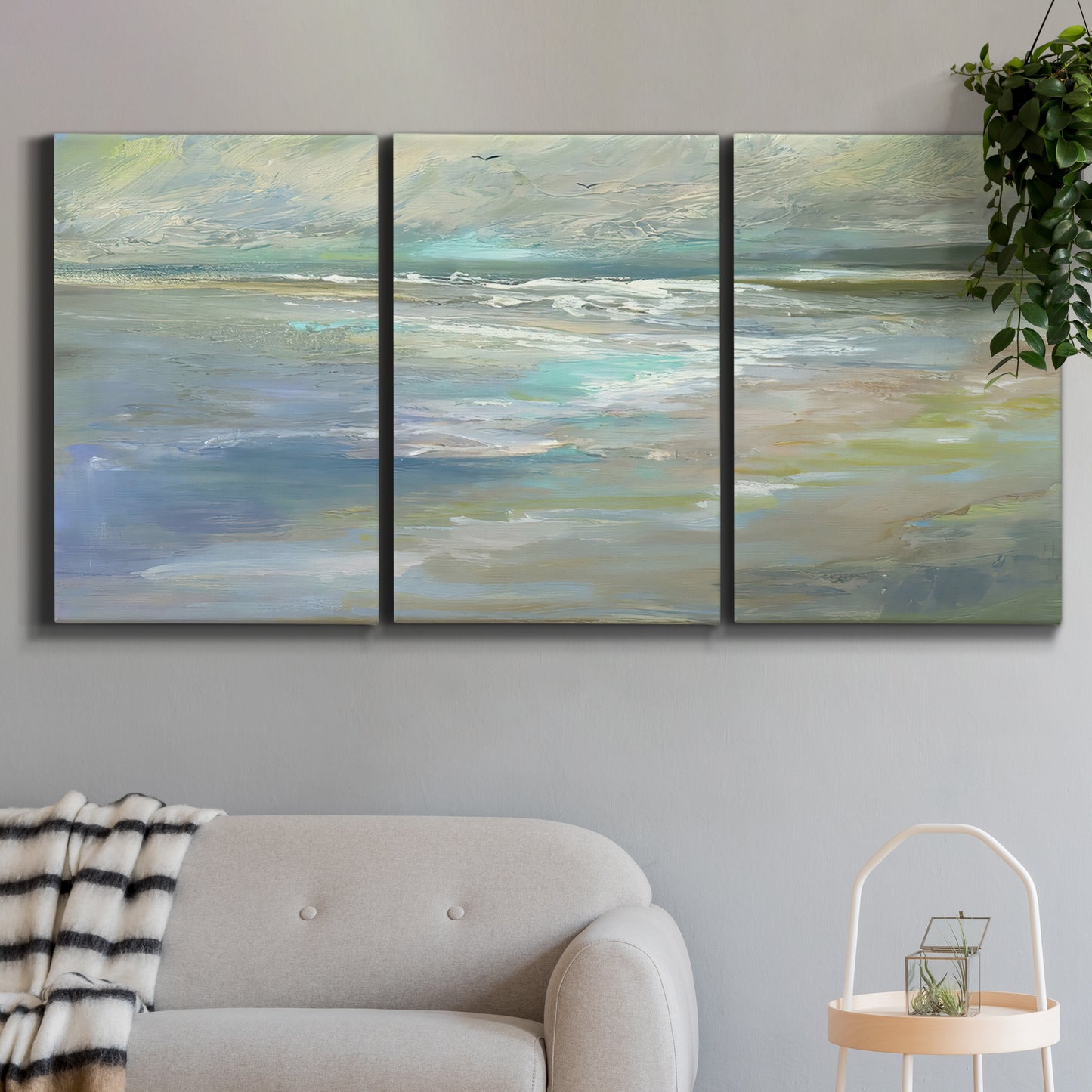Three-panel canvas wall art featuring soft coastal beach light landscape, displayed in a modern living room above a sofa.