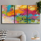 Three-panel canvas wall art featuring expressive abstract sunset tones, displayed in a modern living room above a sofa.