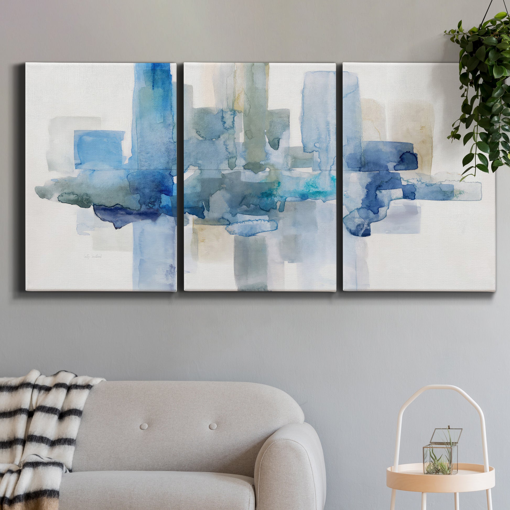 Three-panel canvas wall art featuring minimal urban skyline watercolor, displayed in a modern living room above a sofa.