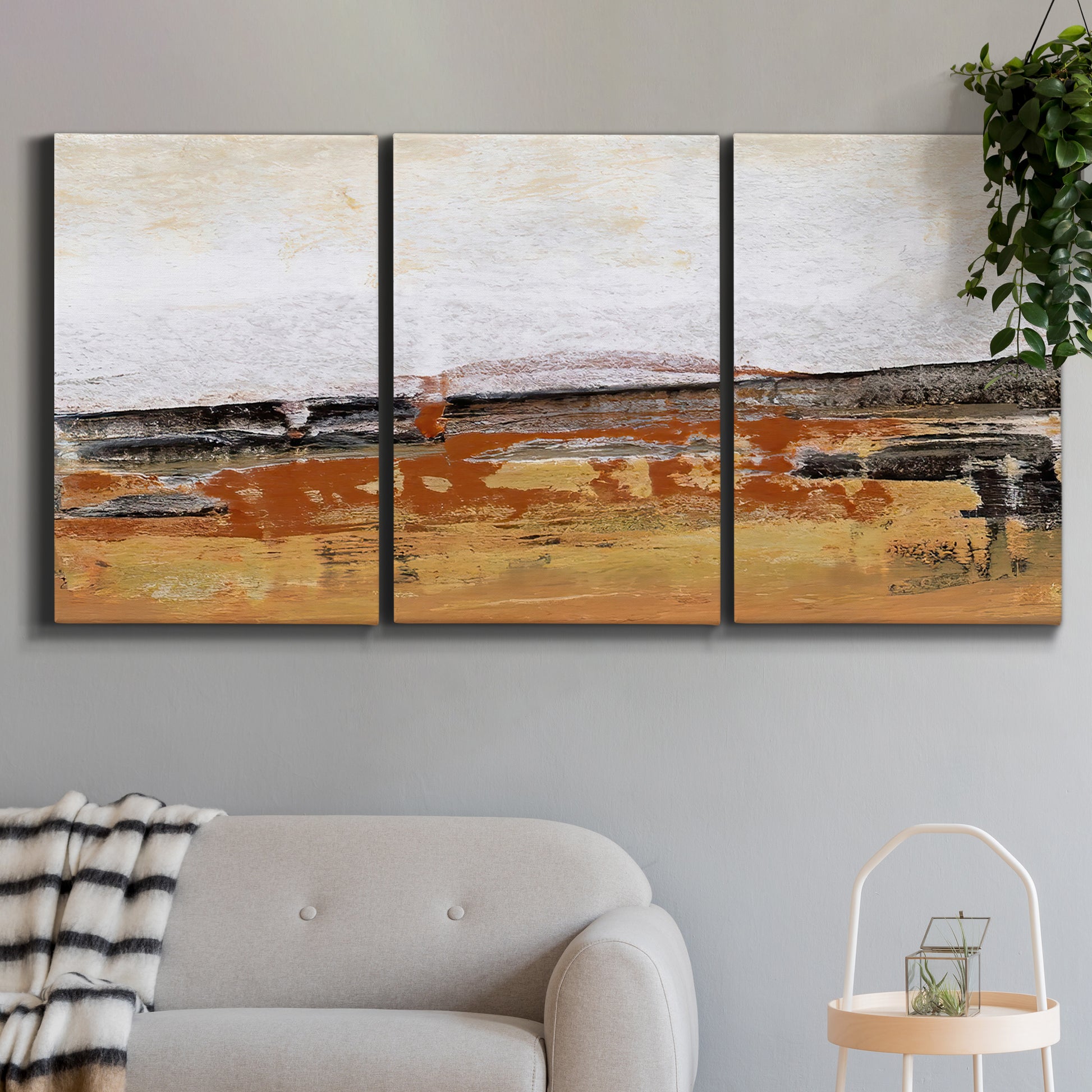 Three-panel canvas wall art featuring abstract bridge landscape in ochre, displayed in a modern living room above a sofa.