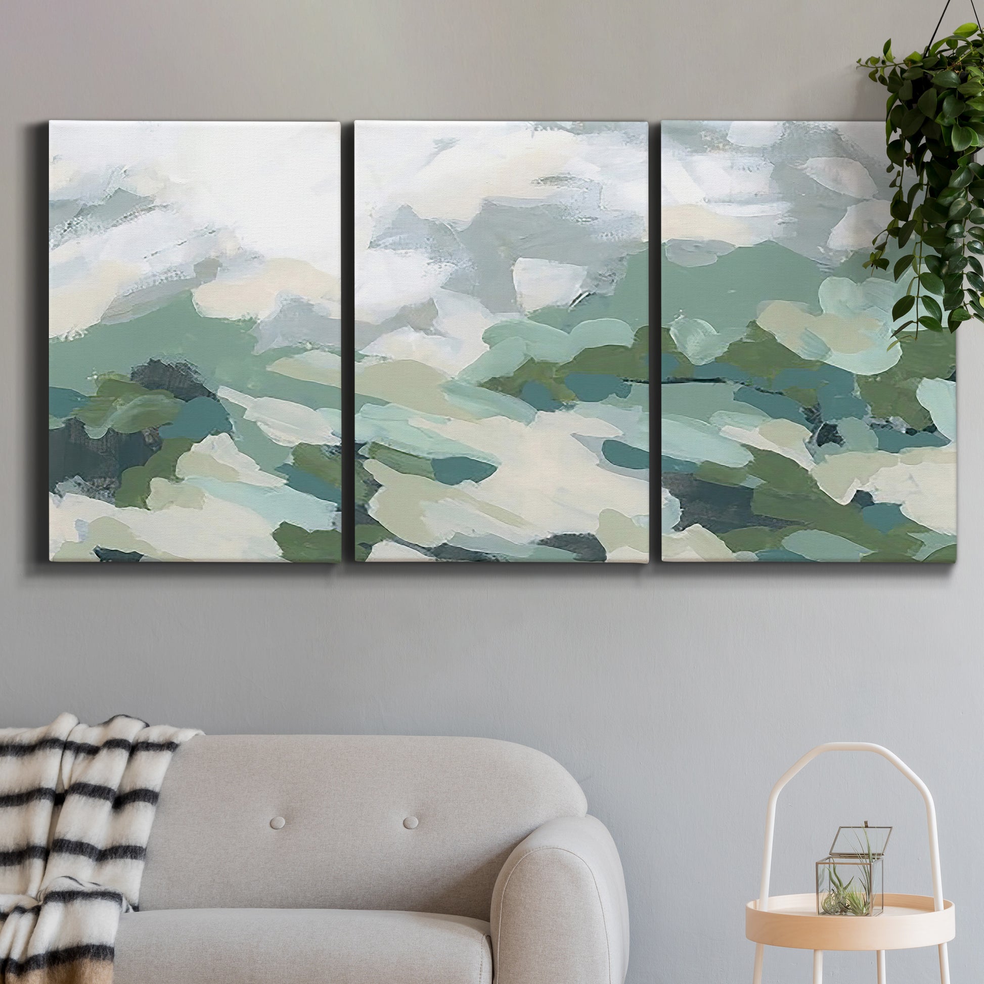 Three-panel canvas wall art featuring lush green hillside rolling landscape, displayed in a modern living room above a sofa.