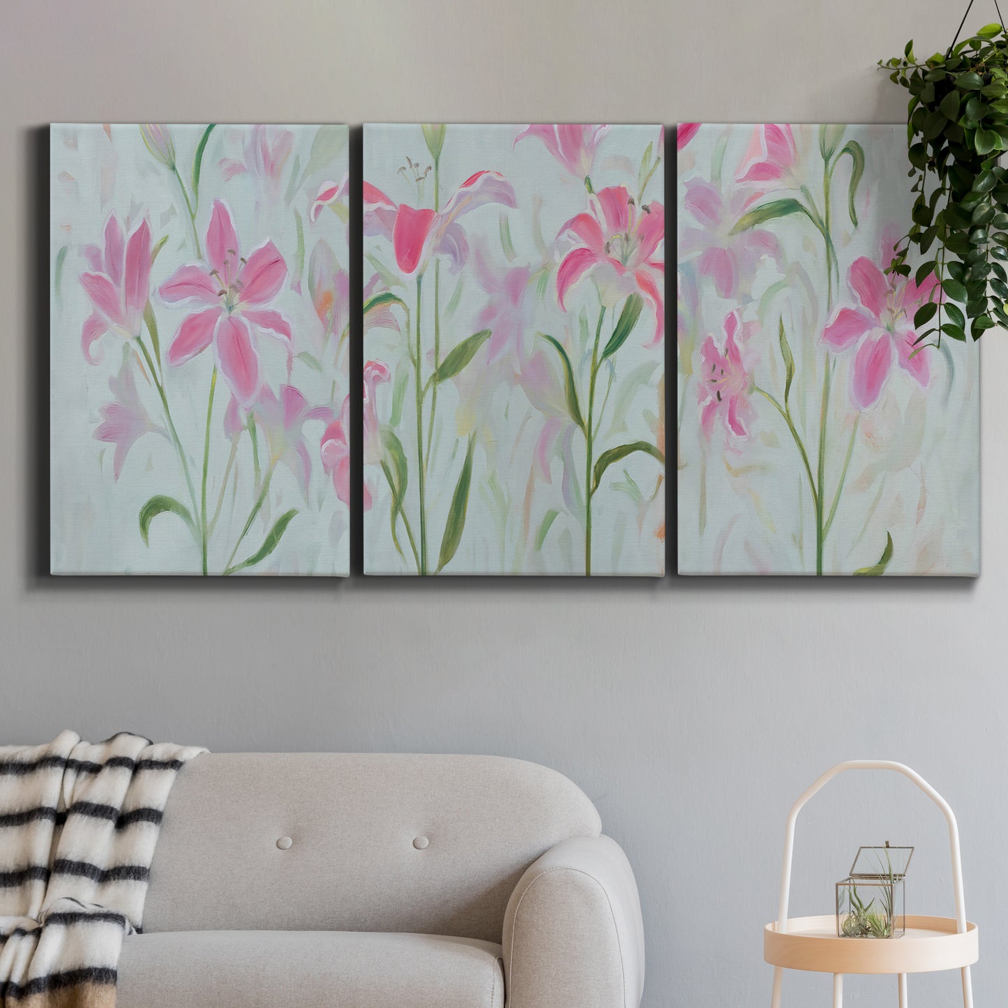Three-panel canvas wall art featuring pink floral trio arrangement, displayed in a modern living room above a sofa.
