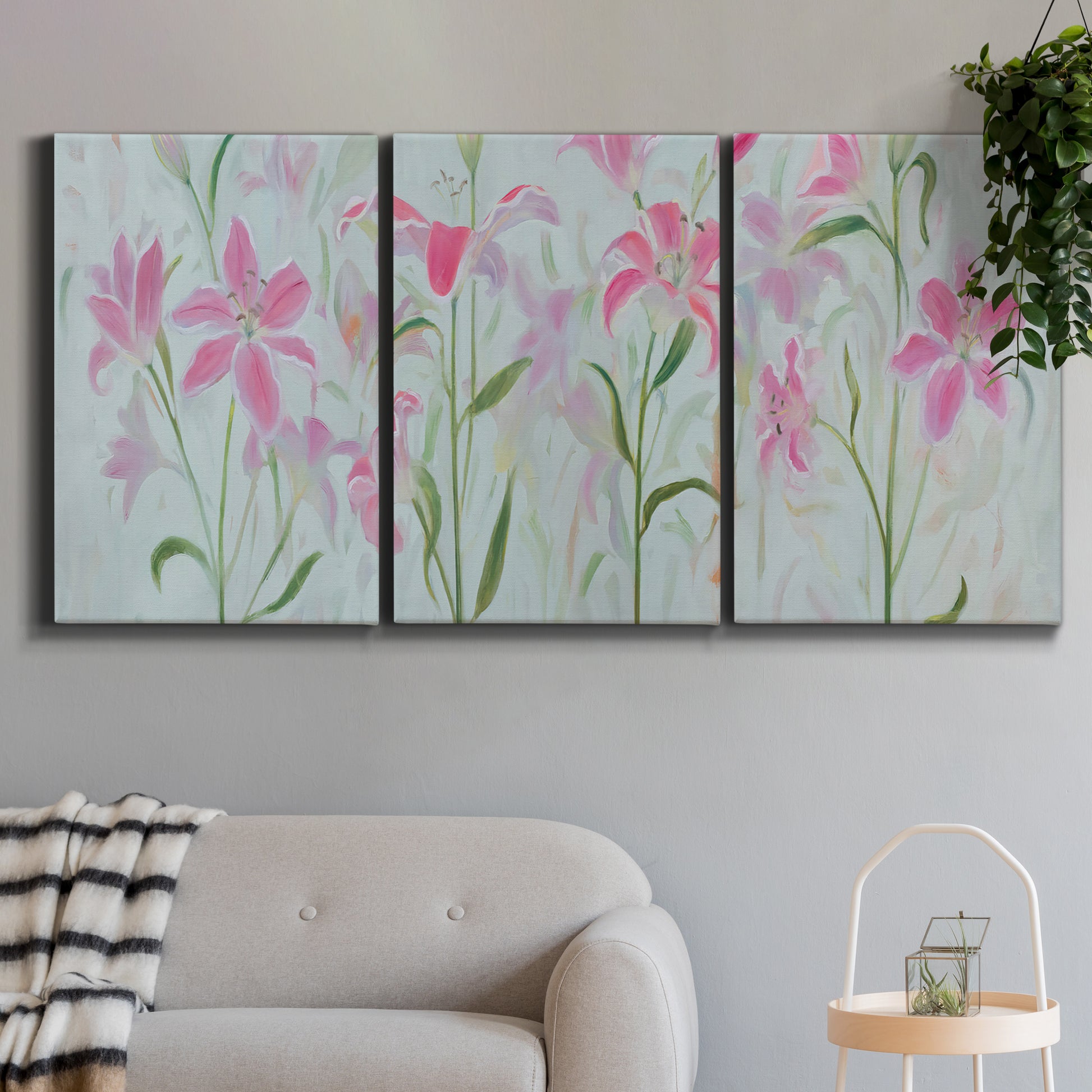 Three-panel canvas wall art featuring pink floral trio arrangement, displayed in a modern living room above a sofa.