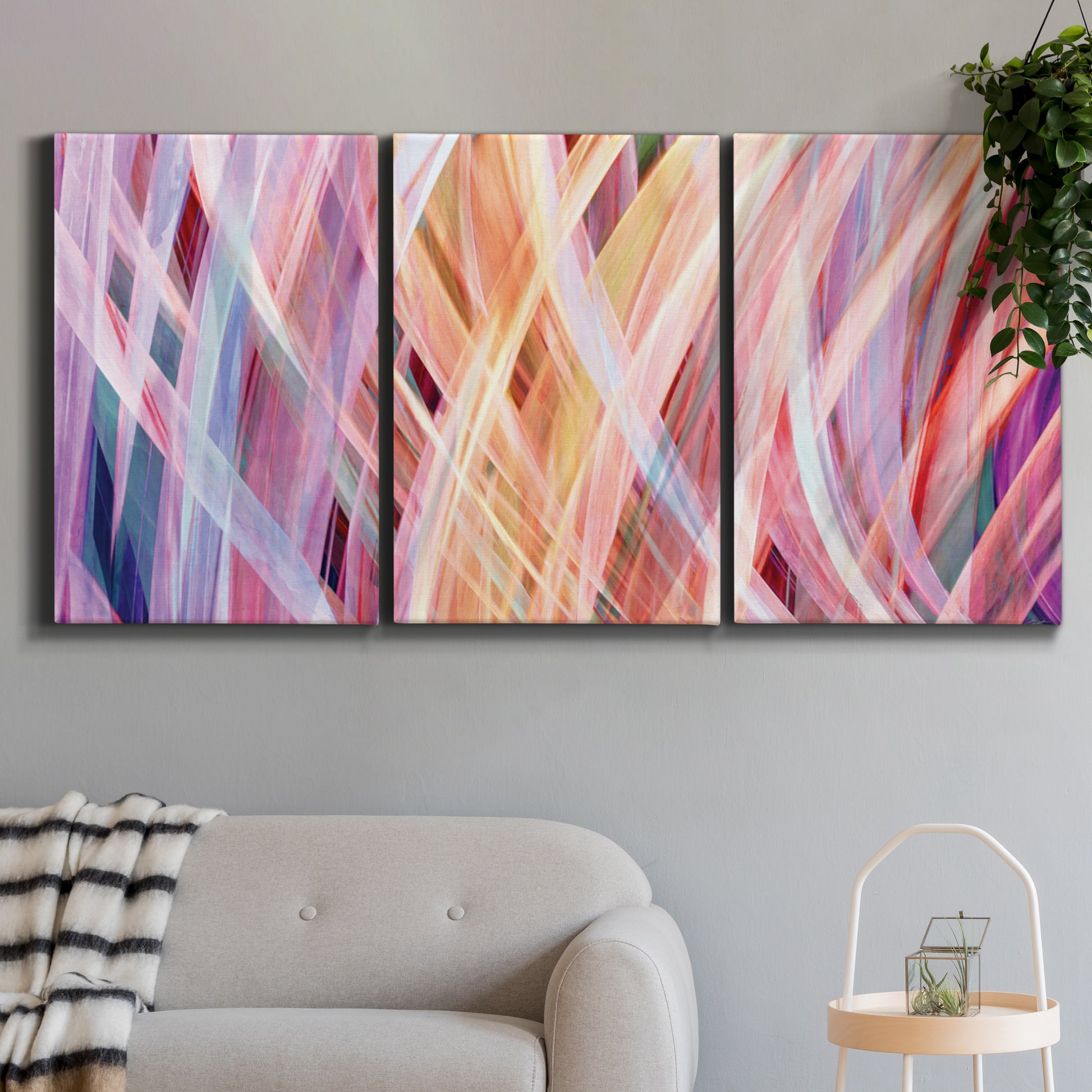 Three-panel canvas wall art featuring layered modern abstract color ribbons, displayed in a modern living room above a sofa.