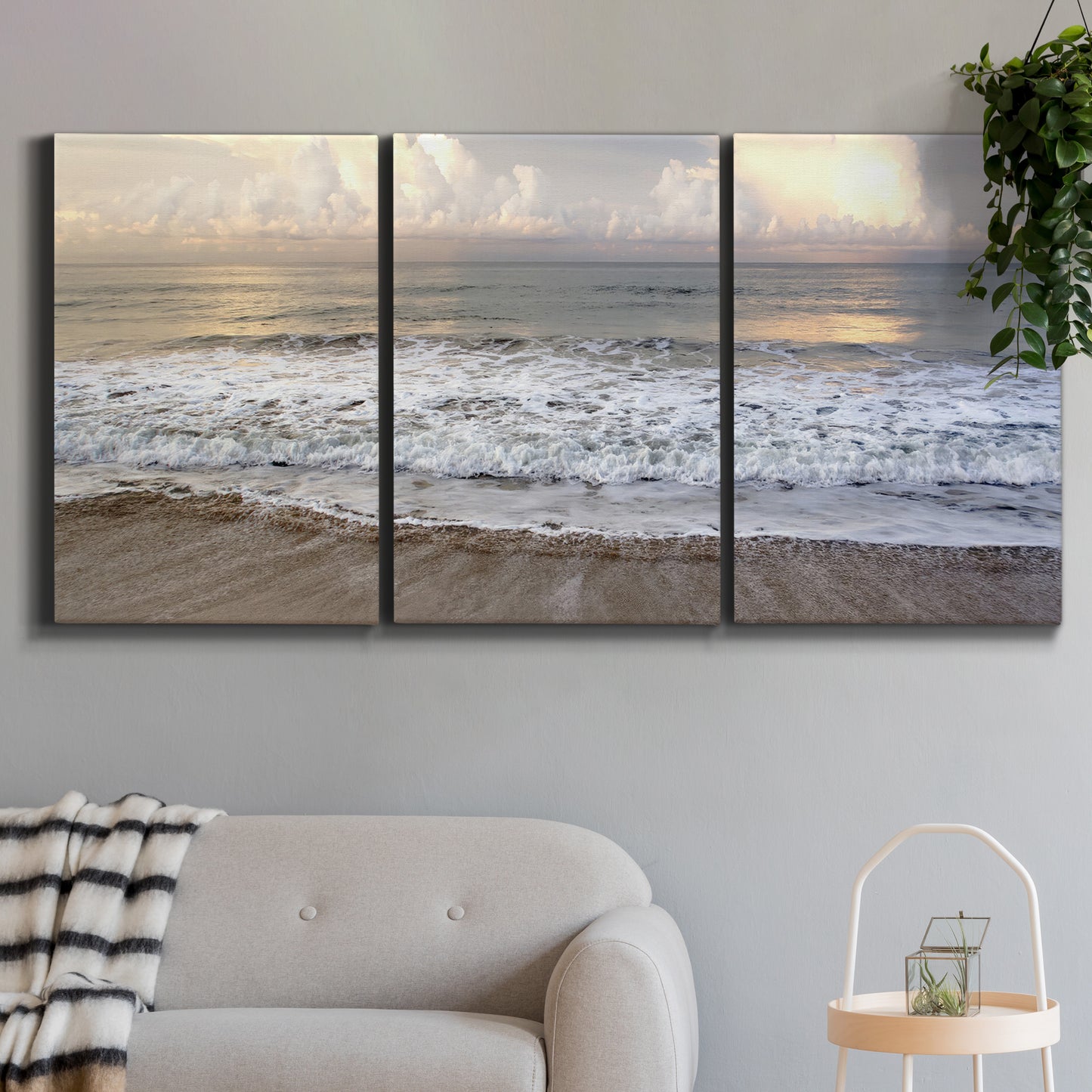 Three-panel canvas wall art featuring calm coastal shoreline seascape, displayed in a modern living room above a sofa.