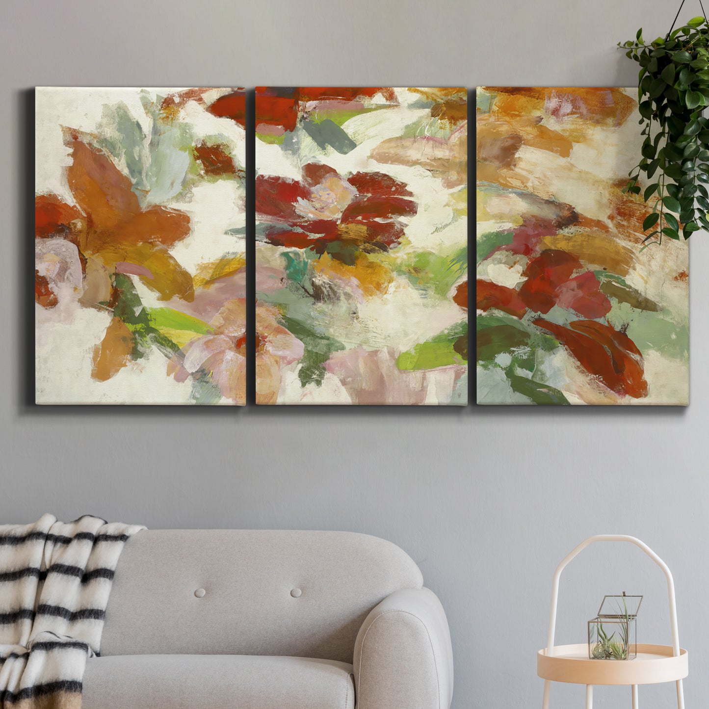 Three-panel canvas wall art featuring layered floral botanical impressions, displayed in a modern living room above a sofa.