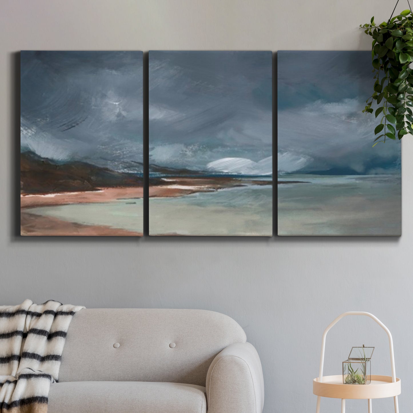 Three-panel canvas wall art featuring stormy sea glass toned coastline, displayed in a modern living room above a sofa.