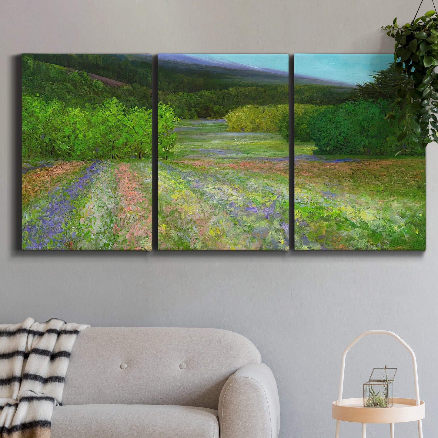 Three-panel canvas wall art featuring fresh spring meadow landscape, displayed in a modern living room above a sofa.